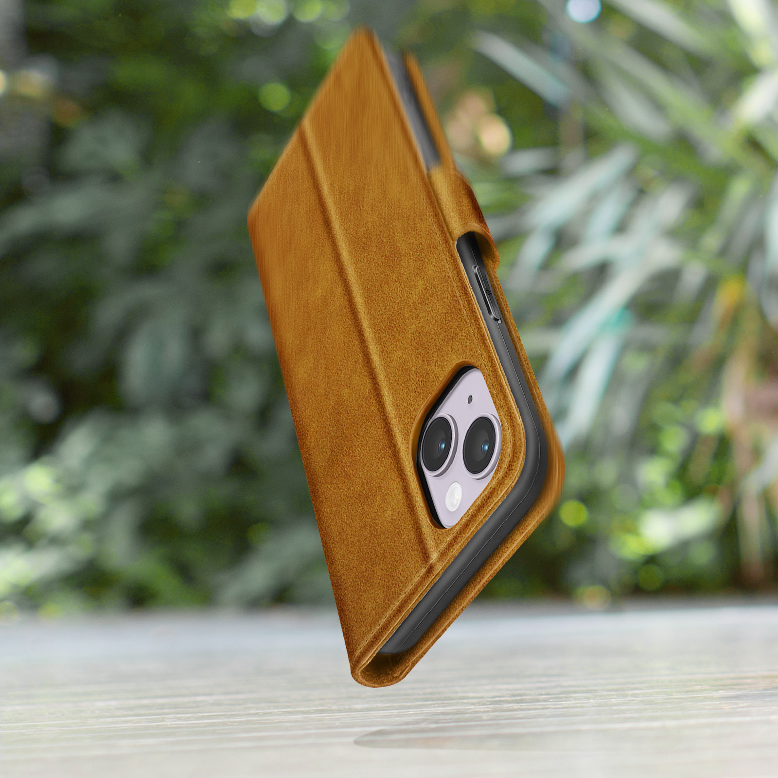 Een bruine telefoonhoes met twee camera's, tegen een wazig groen.