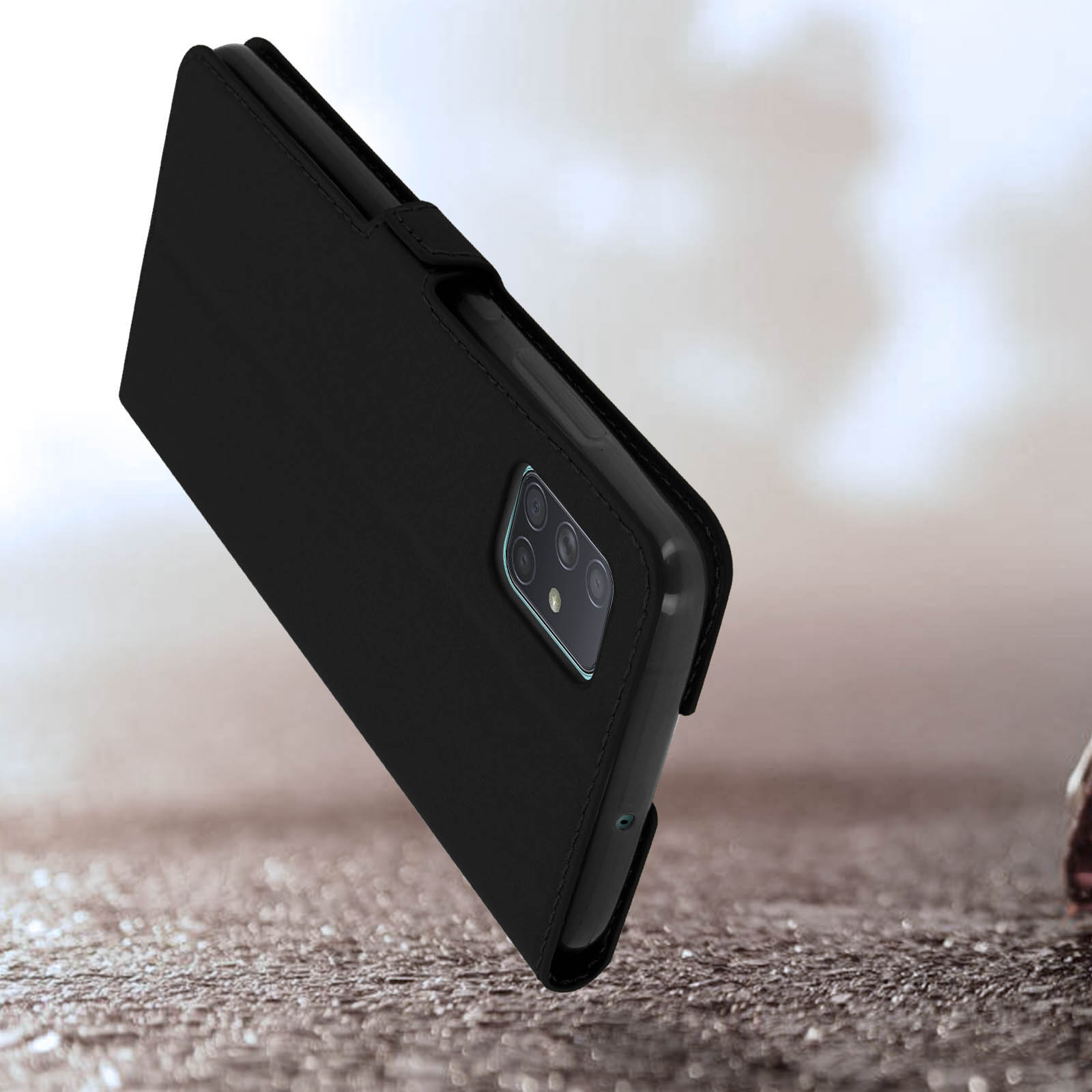 Smartphone nero con quad camera in custodia flip su superficie rocciosa.