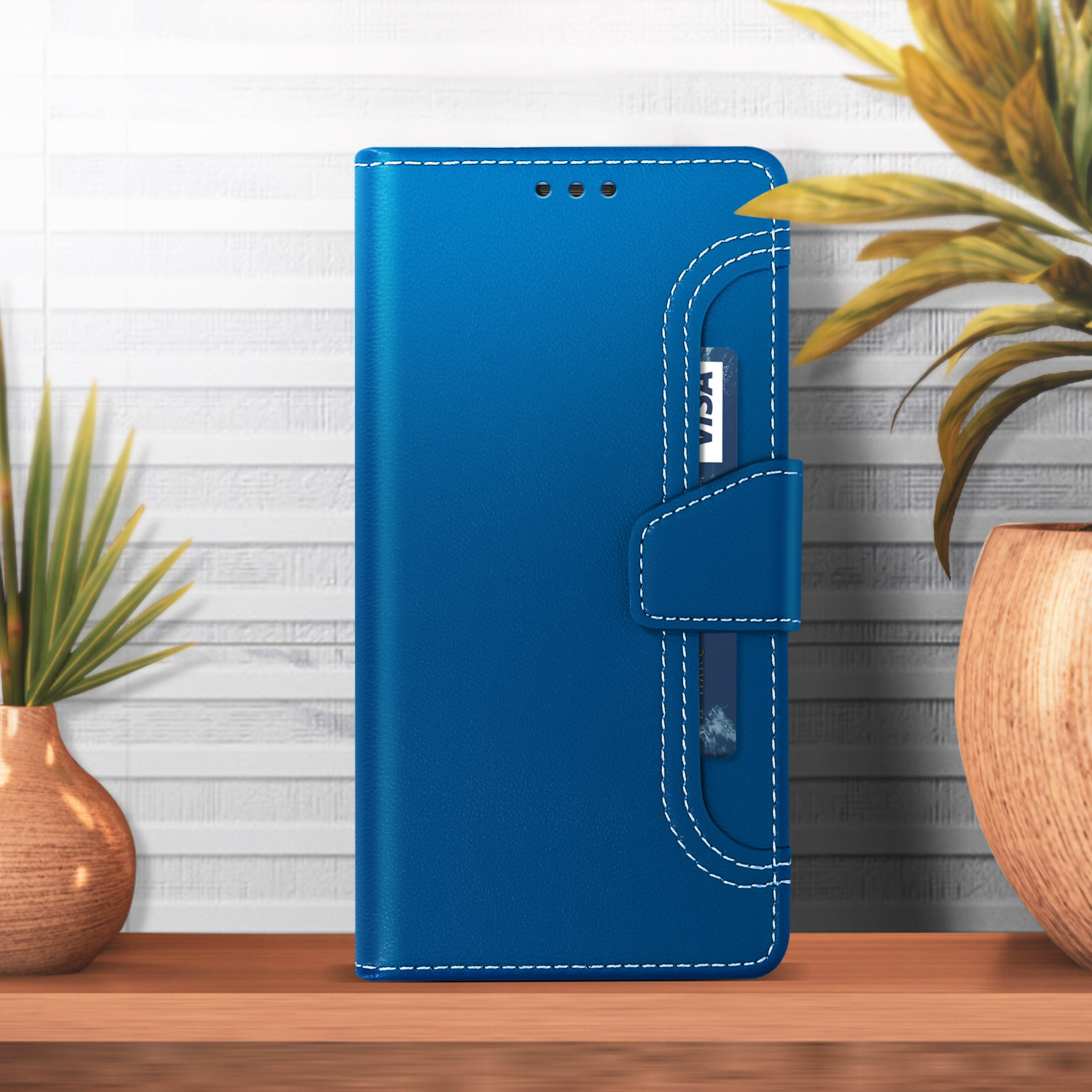 Étui portefeuille bleu pour téléphone avec fente pour carte sur table en bois, plantes à proximité.