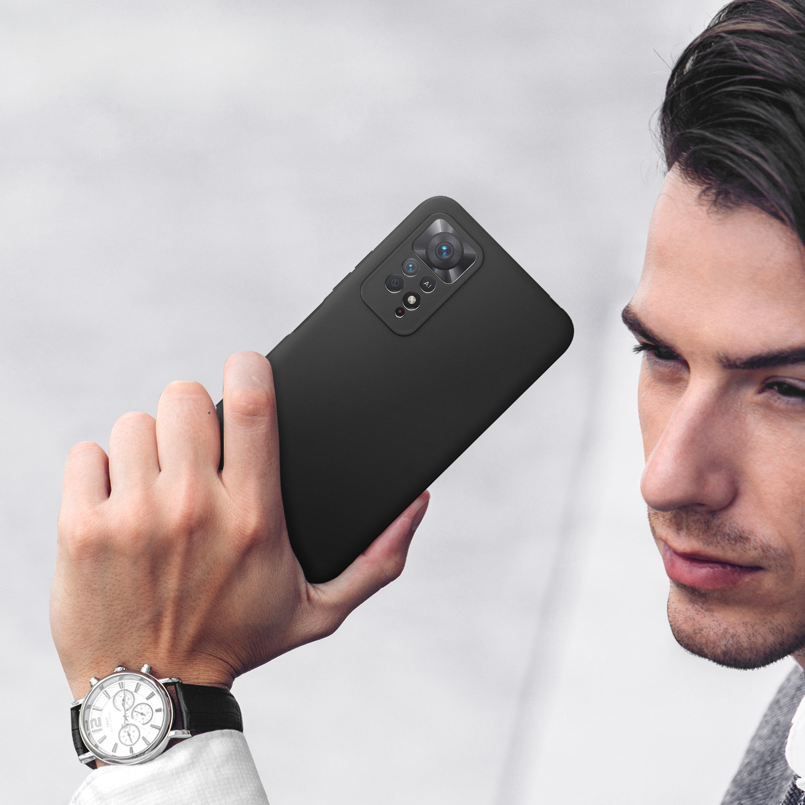 Een man houdt een zwarte smartphone met camera vast.