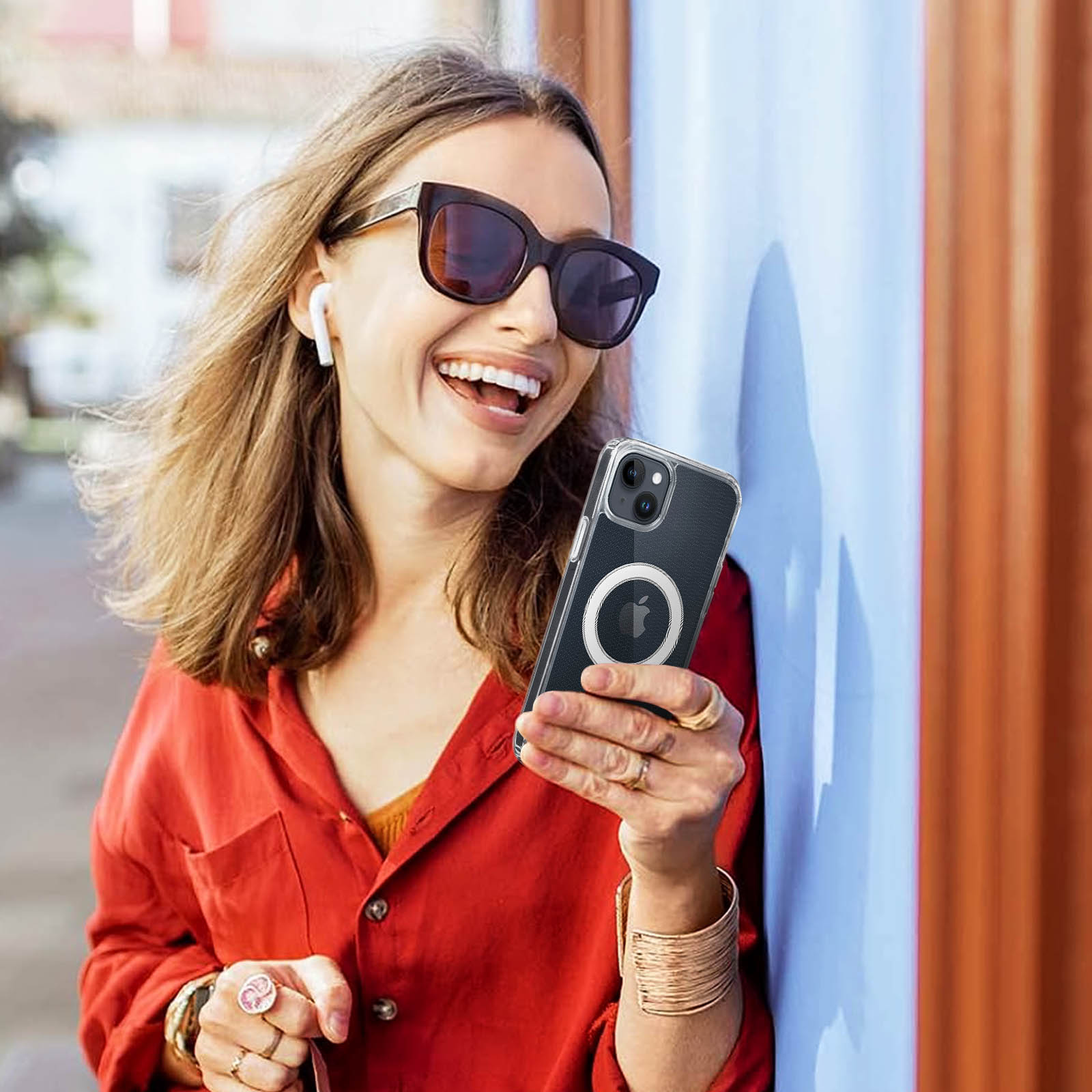 Vrouw met koptelefoon en zonnebril lacht en houdt een smartphone in hoesje vast.