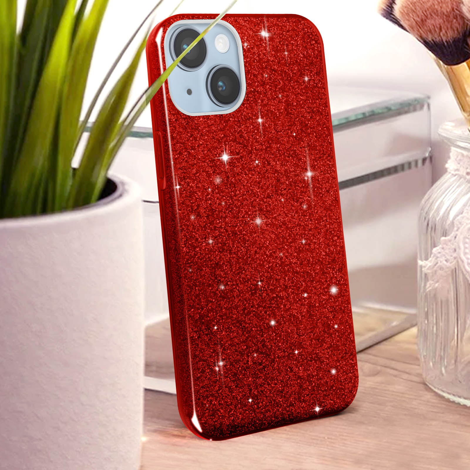 Rode glitter telefoonhoes met twee camera's, naast een pot met groene planten.