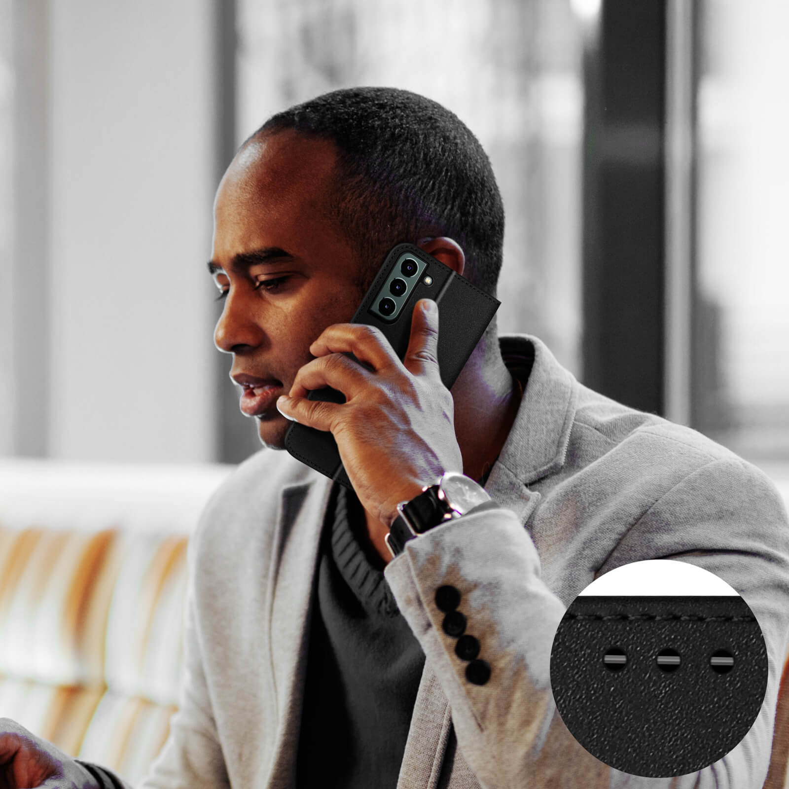 Un homme de couleur parlant au téléphone, portant un costume gris et une montre.