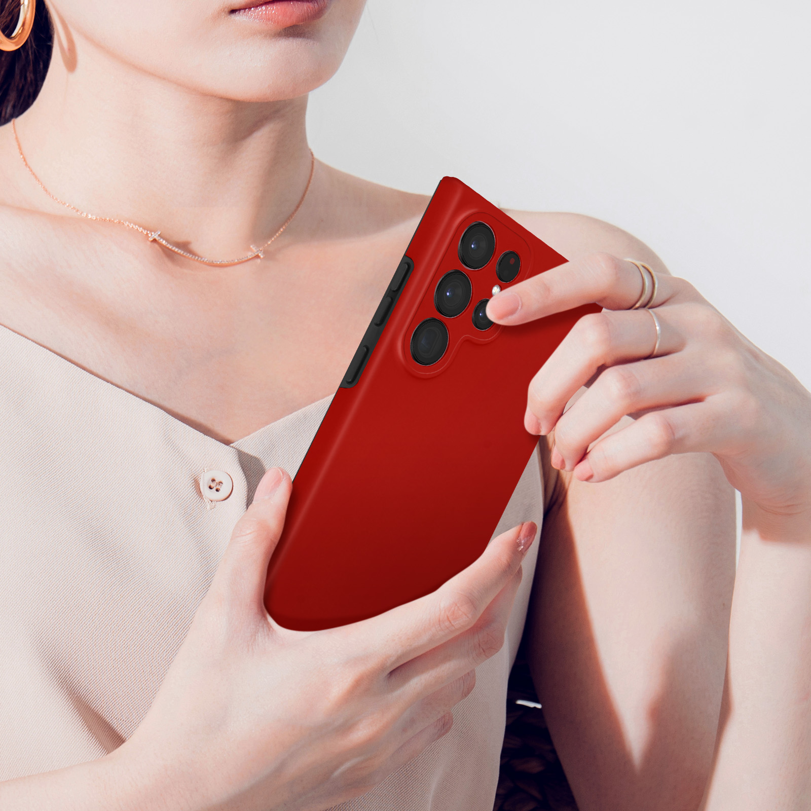 Une femme tient un smartphone rouge avec quatre objectifs.