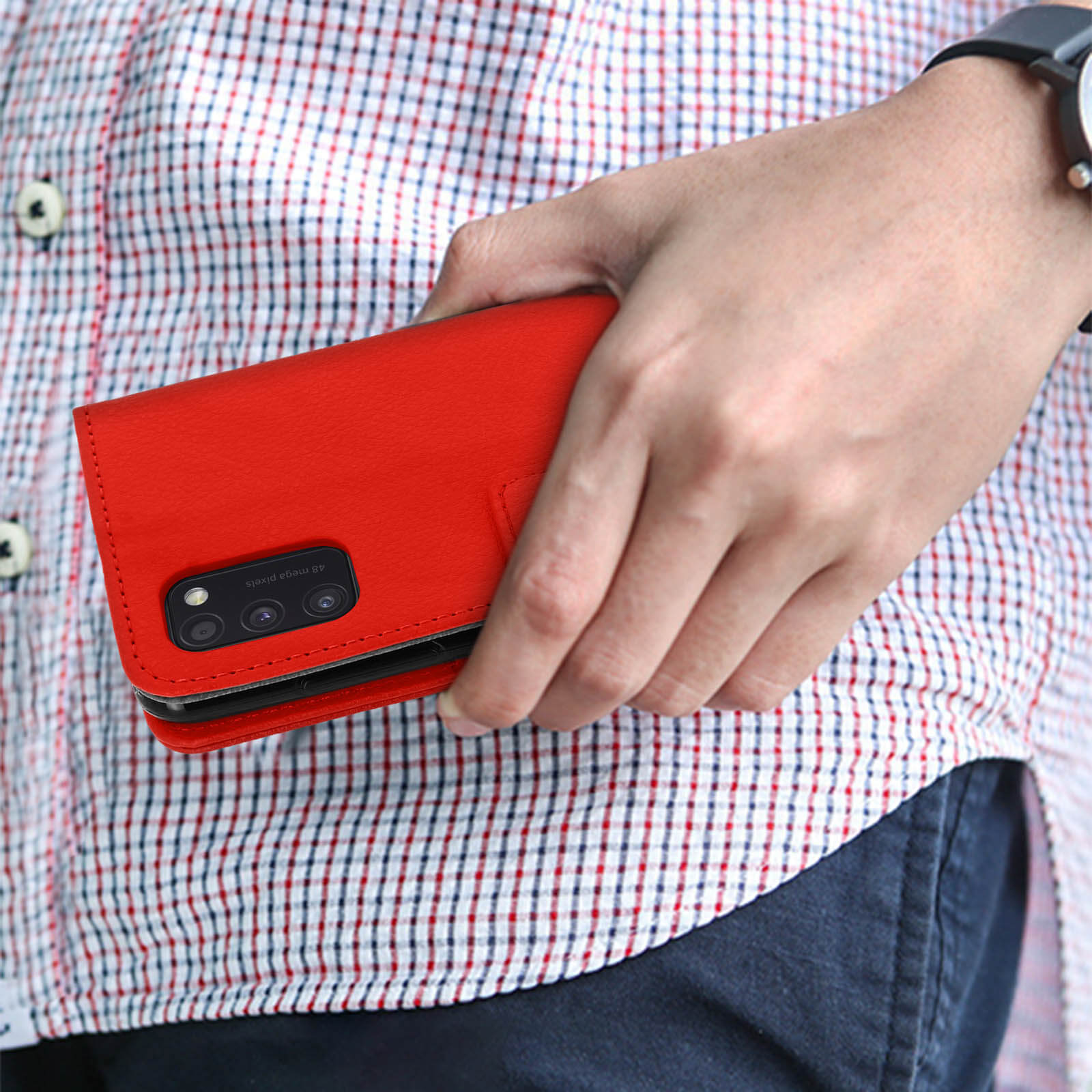 Un étui de téléphone rouge avec caméras tenu dans une main. La personne porte une chemise à carreaux.