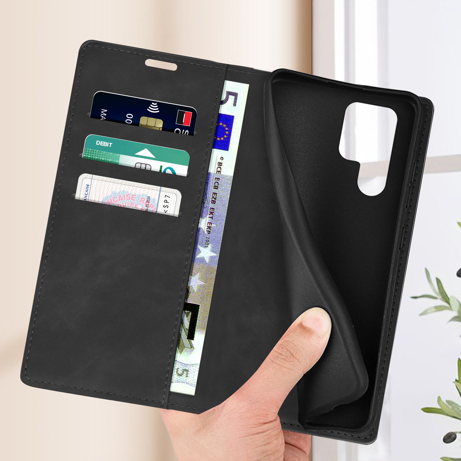 Zwarte telefoonhoes met kaartsleuven en bankbiljetten, in de hand gehouden.