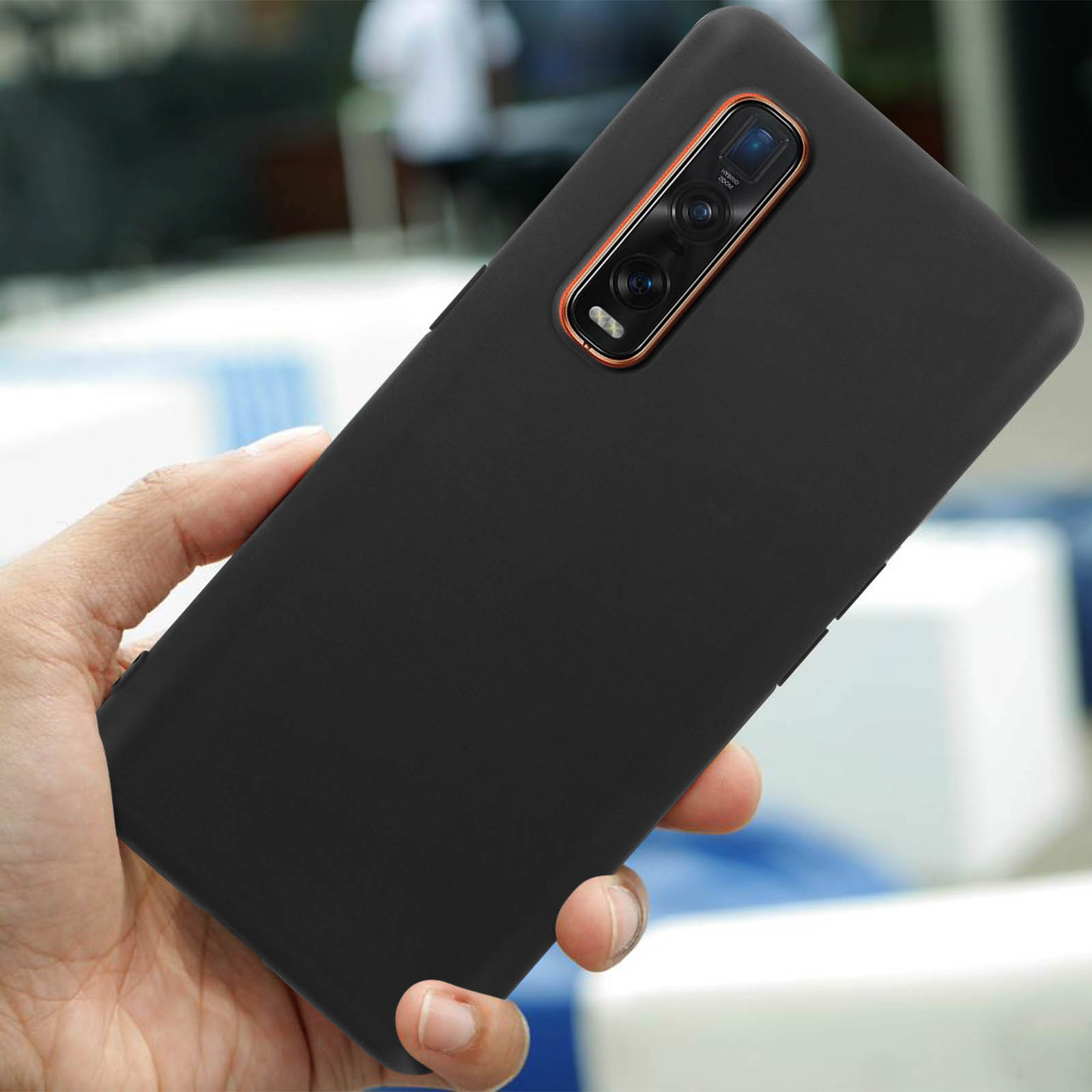 Een hand houdt een zwarte smartphone met camerapaneel vast.