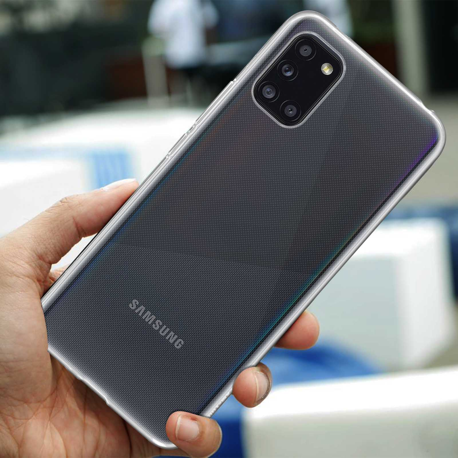 Une main tient un smartphone Samsung avec appareil photo quadruple. L'arrière-plan est flou.
