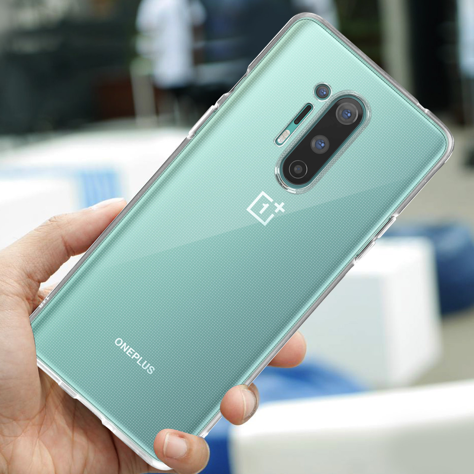Una mano tiene un telefono con cover trasparente, retro verde e tre fotocamere.