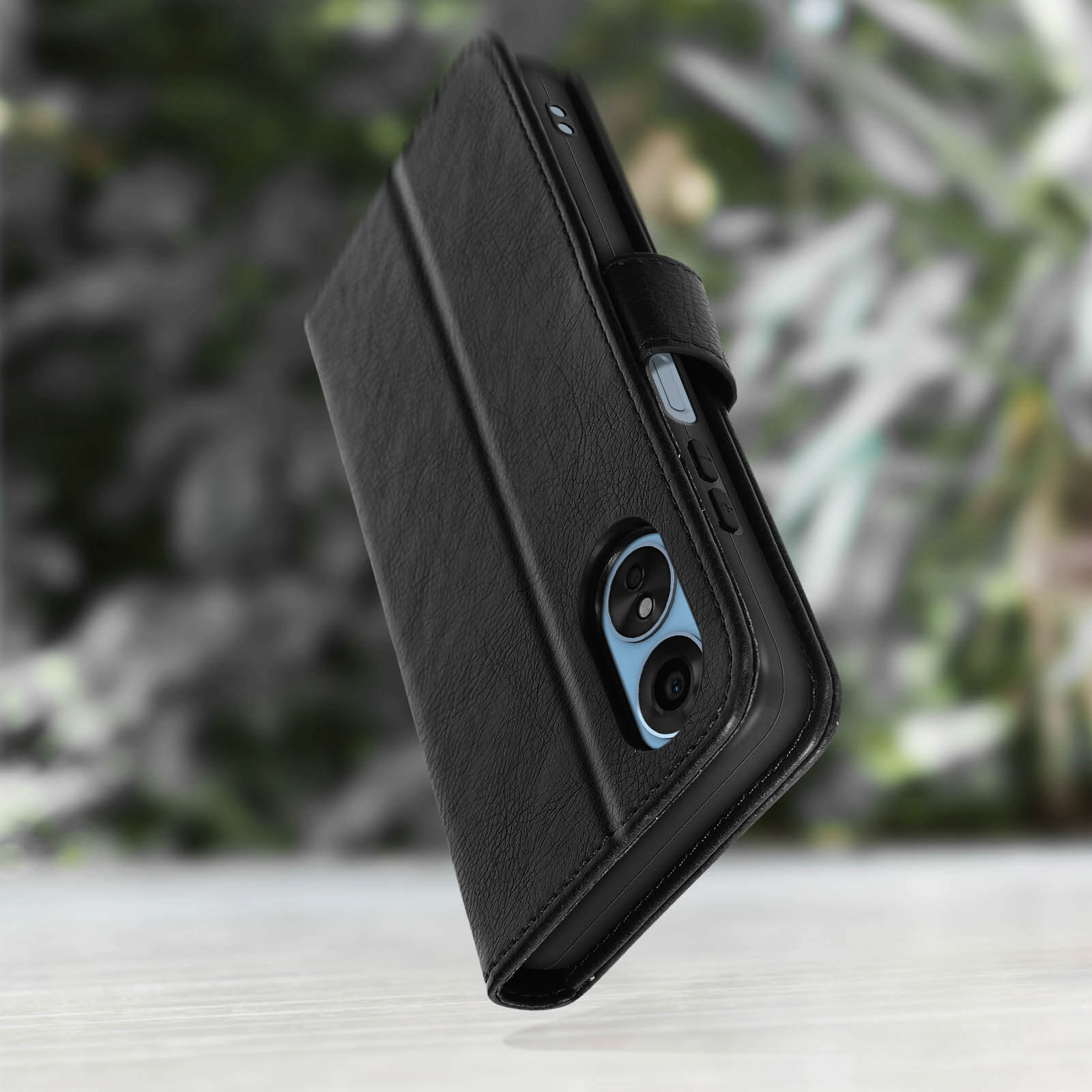 Étui de téléphone en cuir noir avec découpes caméra, sur surface claire