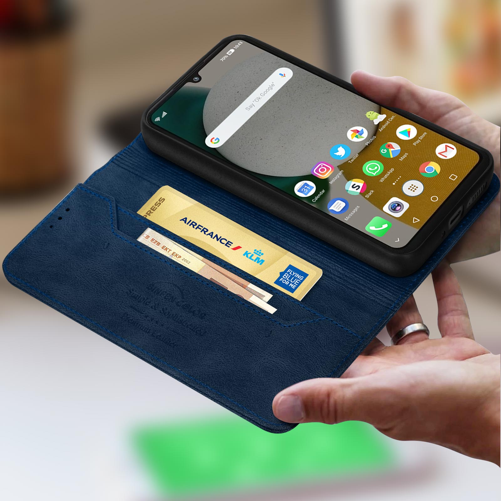 Handen houden een blauwe lederen hoes vast met een smartphone en een Air France/KLM-kaart.