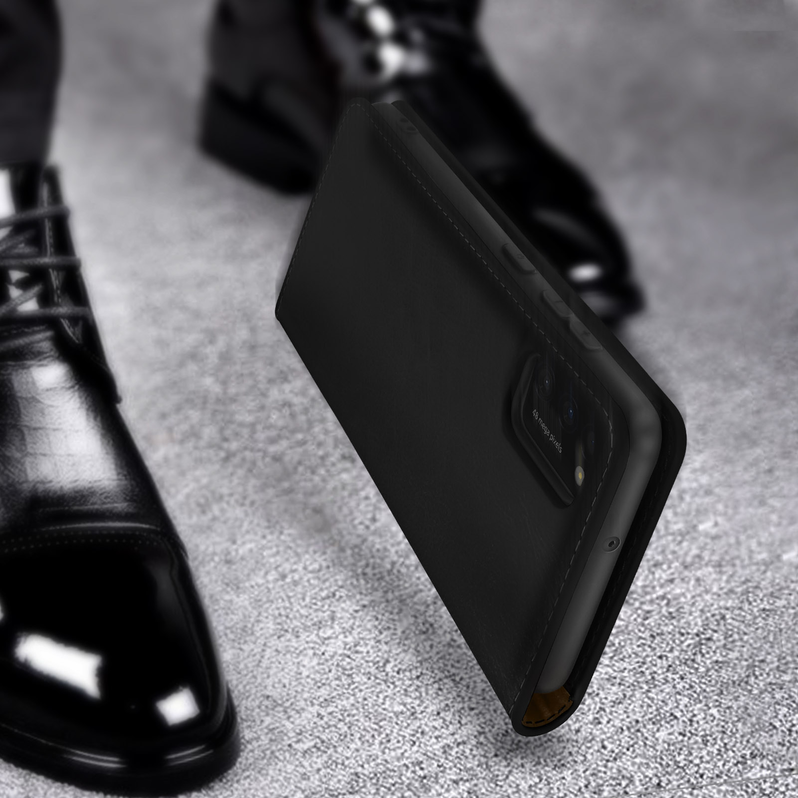 Zwarte flipcase voor smartphone naast glanzende zwarte nette herenschoenen.