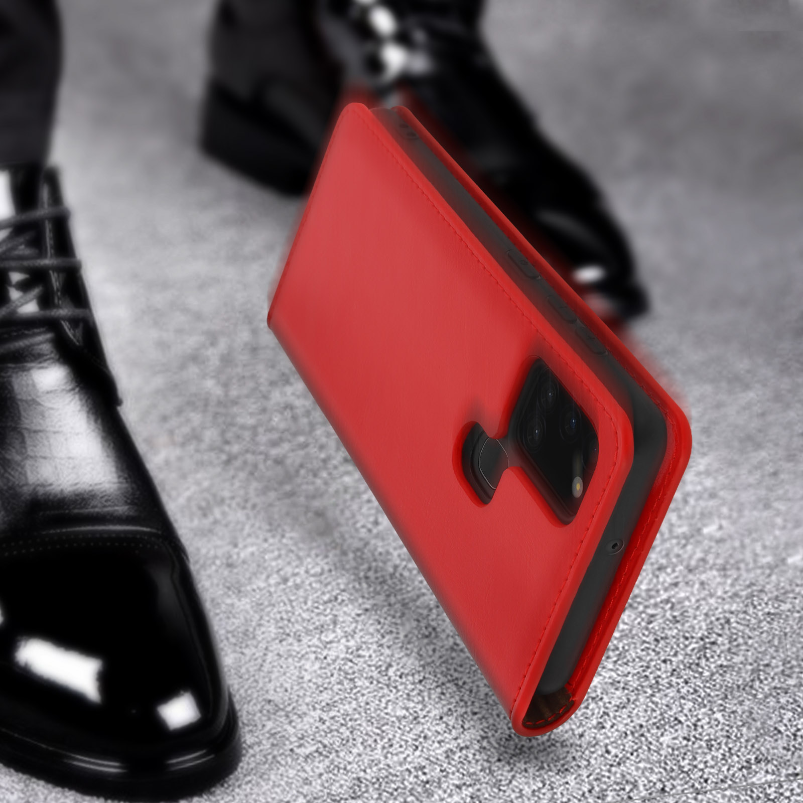 Étui de téléphone rouge avec système de caméra sur surface grise à côté de chaussures noires.