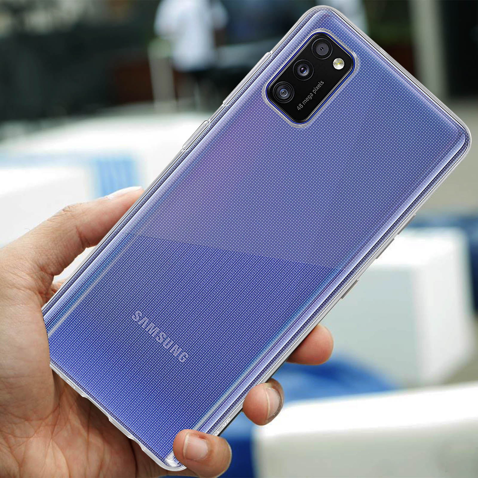 Hand houdt een blauwe Samsung smartphone met quad camera vast. Wazige achtergrond.