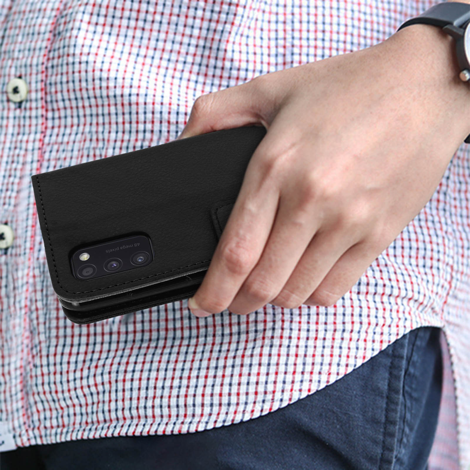 Une personne tient un étui de téléphone noir avec un téléphone à l'intérieur.