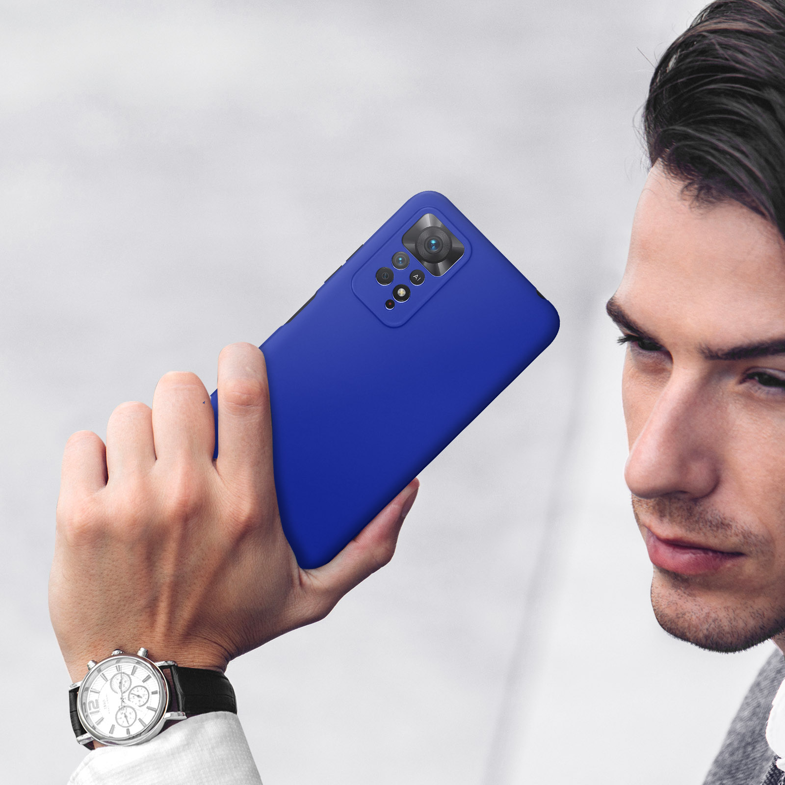 Un homme tenant un smartphone bleu avec appareil photo dans sa main droite.