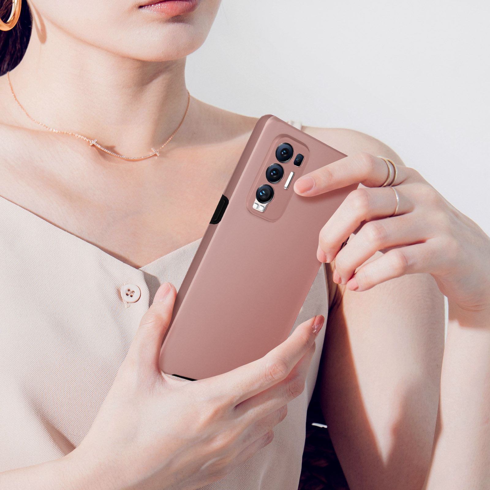 Een persoon houdt een roze telefoon met drie camera's vast.