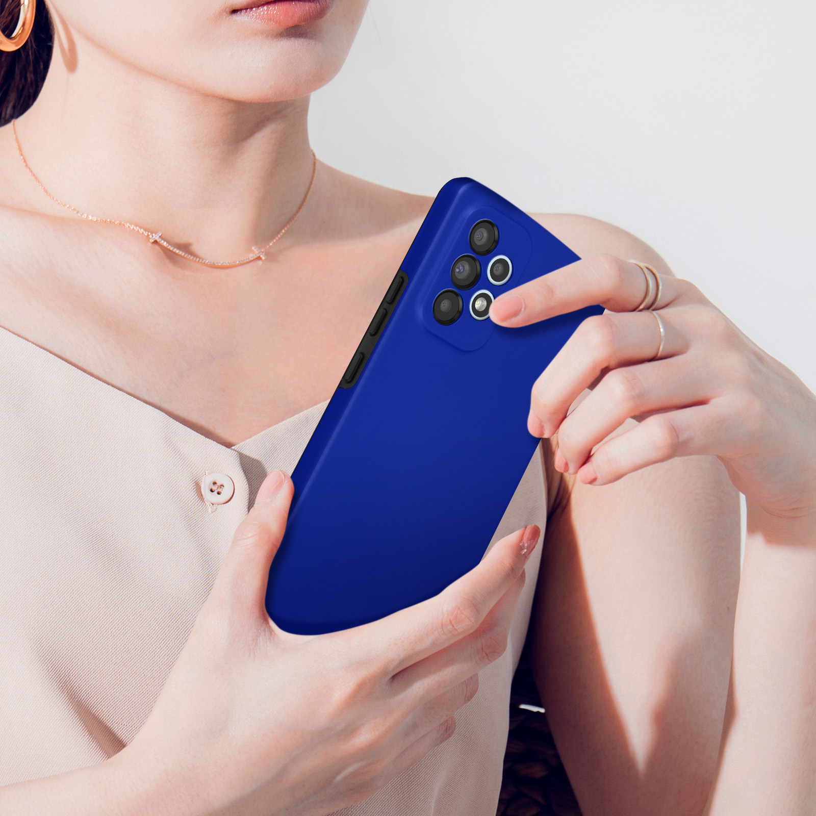 Une femme tient un smartphone bleu avec quatre caméras.