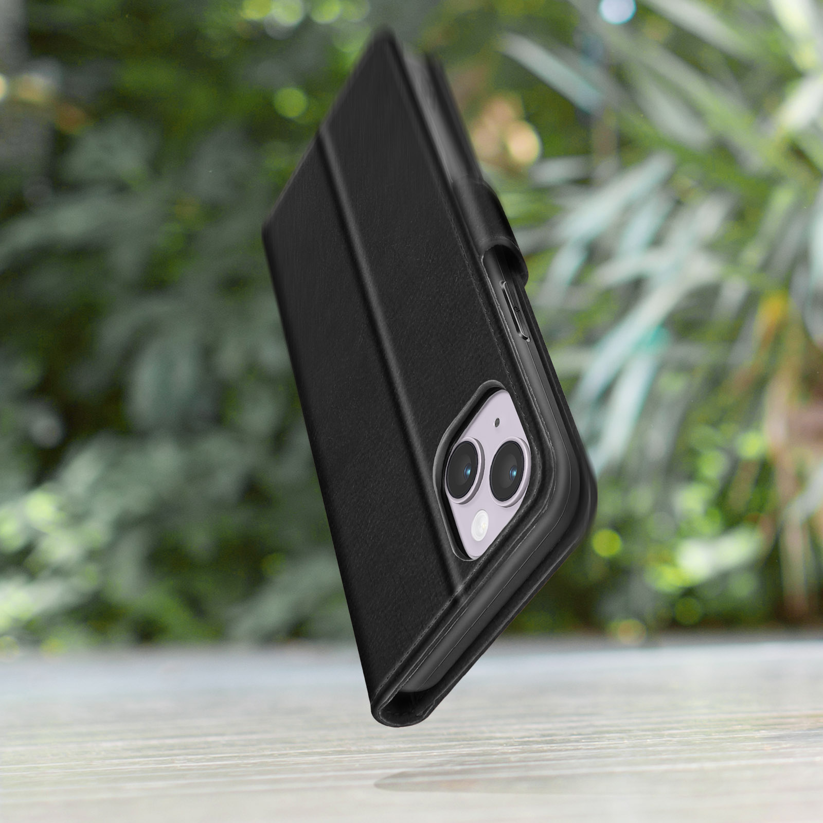Zwarte telefoonhoes op hout, groene bokeh achtergrond.