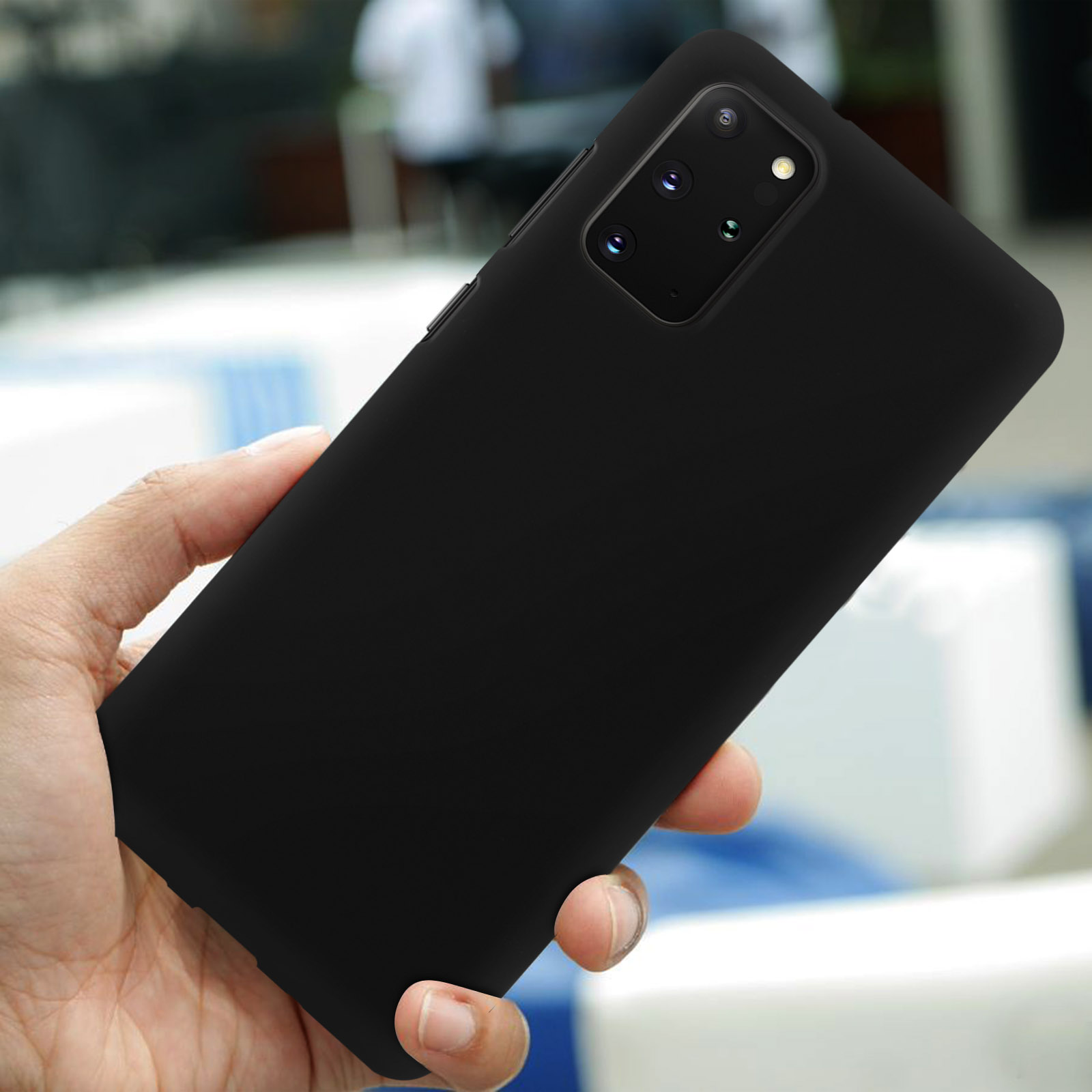 Téléphone noir avec quatre caméras tenu en main. Arrière-plan flou.