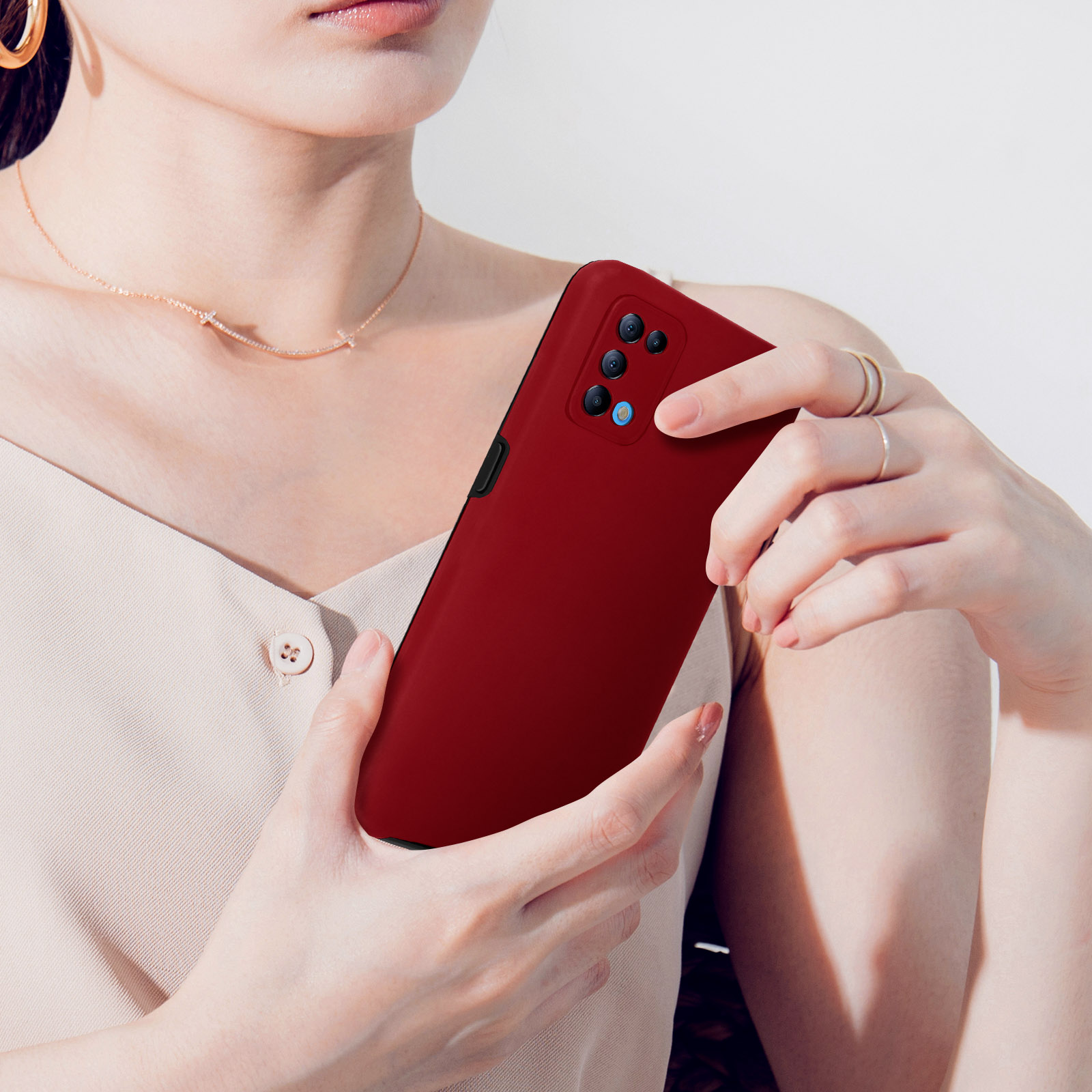 Una persona tiene un telefono cellulare rosso scuro con quattro fotocamere.