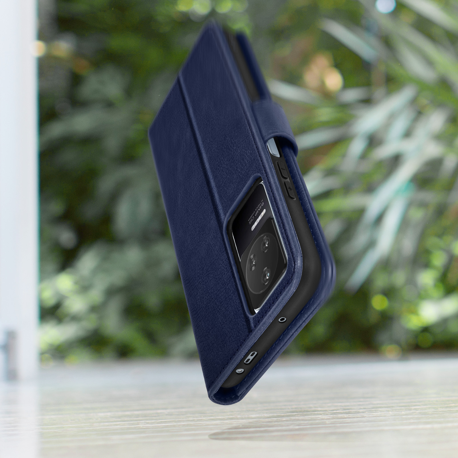Étui à rabat bleu foncé pour téléphone avec appareil photo sur table.