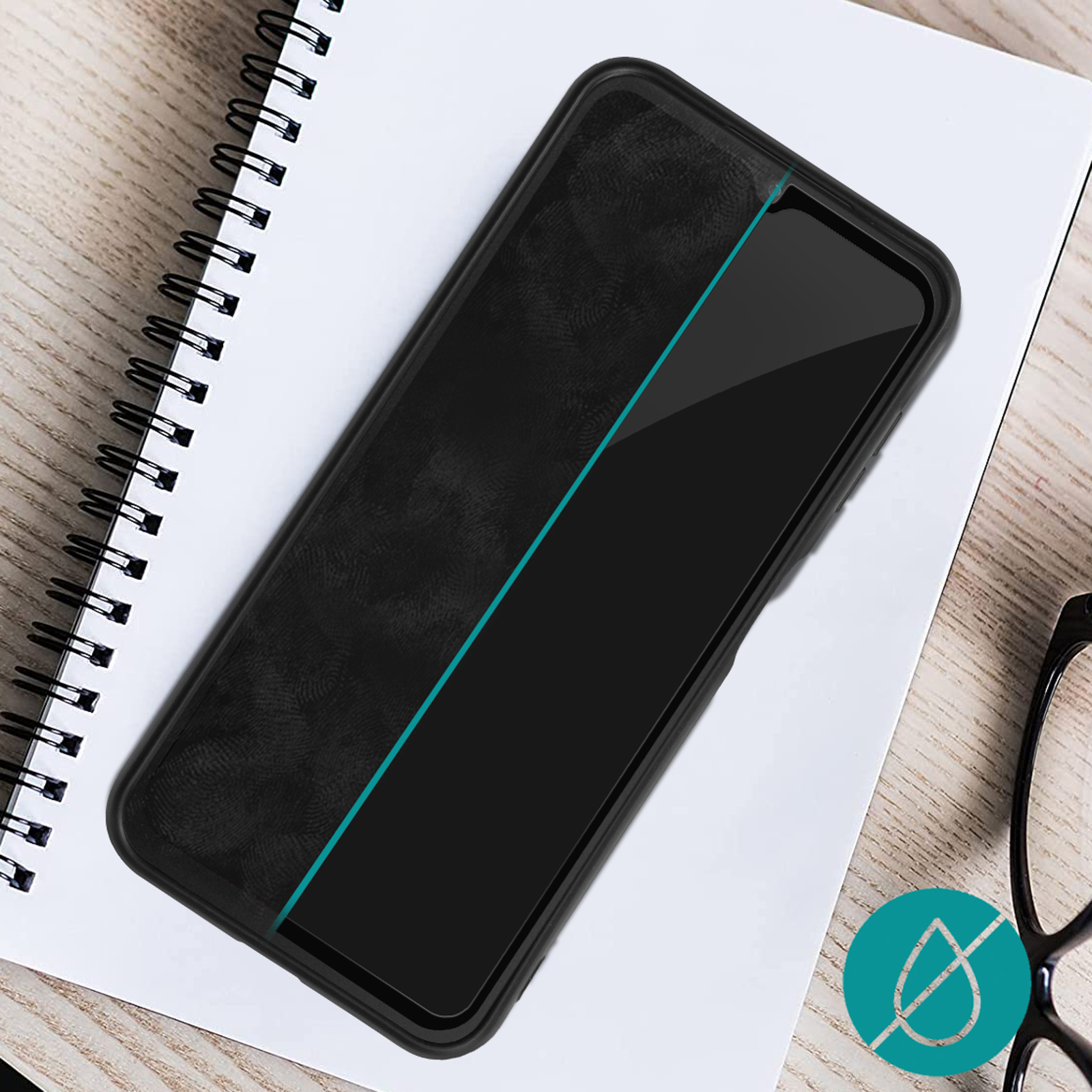 Smartphone noir sur carnet avec bande bleue. Lunettes à droite.