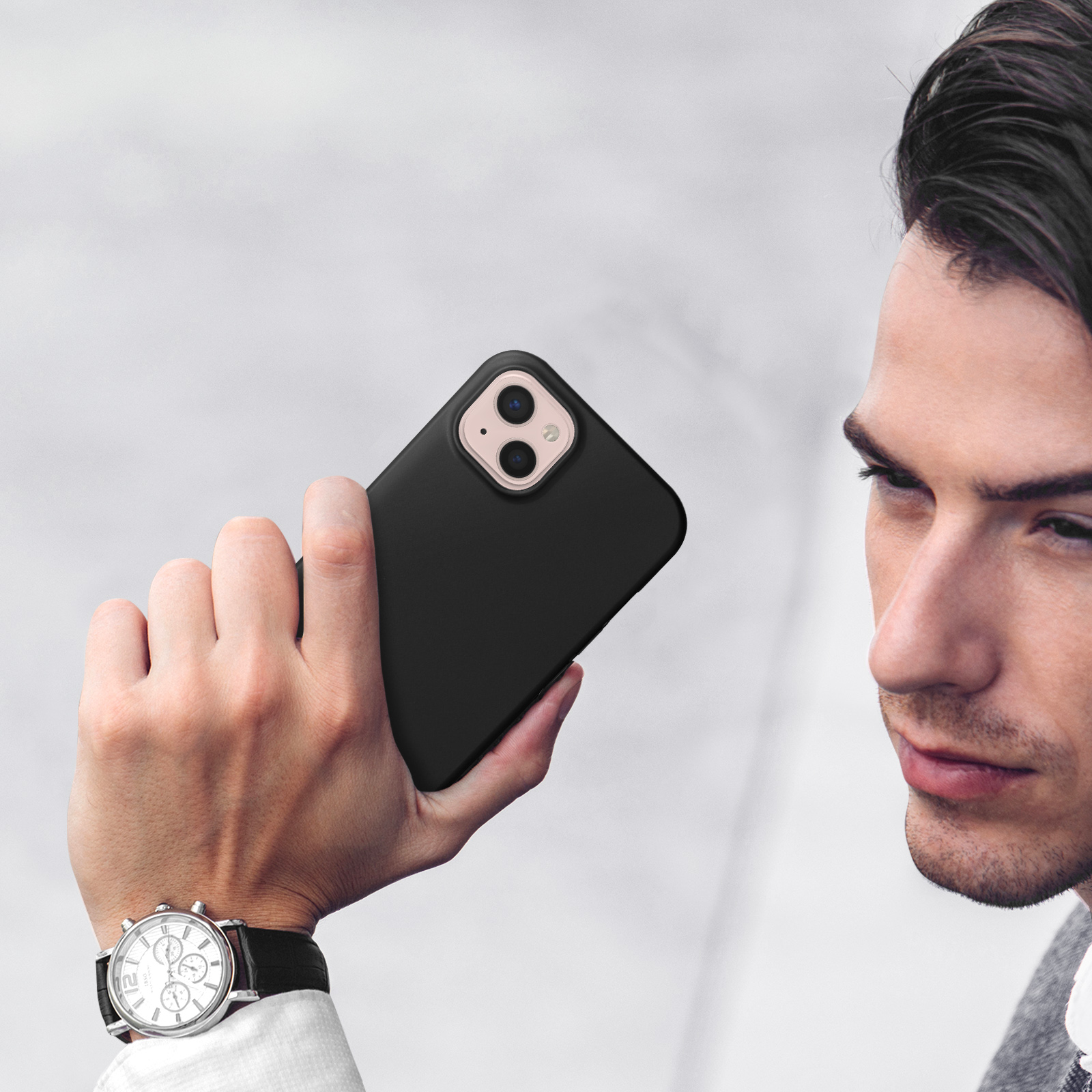 Uomo tiene un iPhone nero con doppia fotocamera. Indossa un orologio.