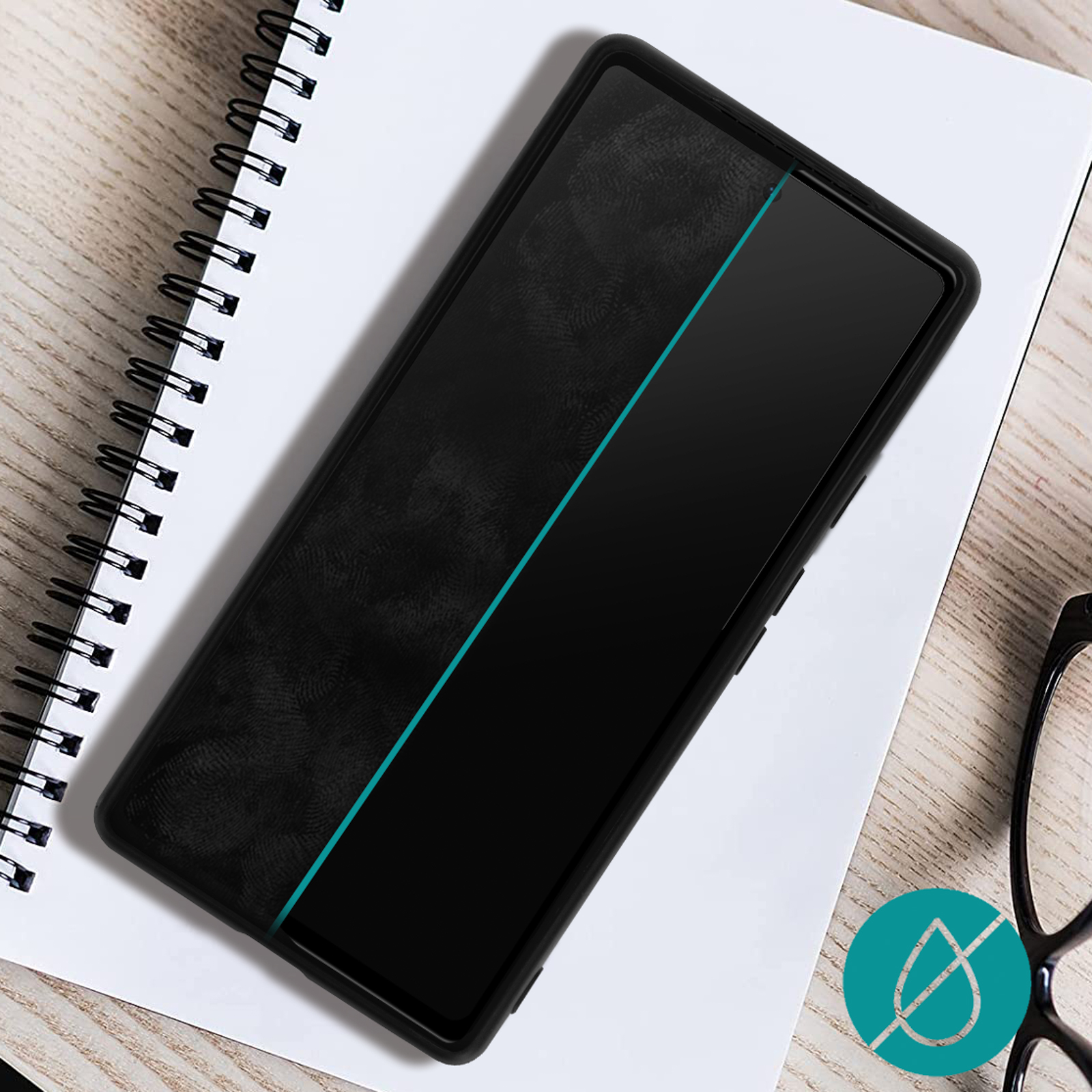 Smartphone noir sur carnet avec bande bleue et lunettes.