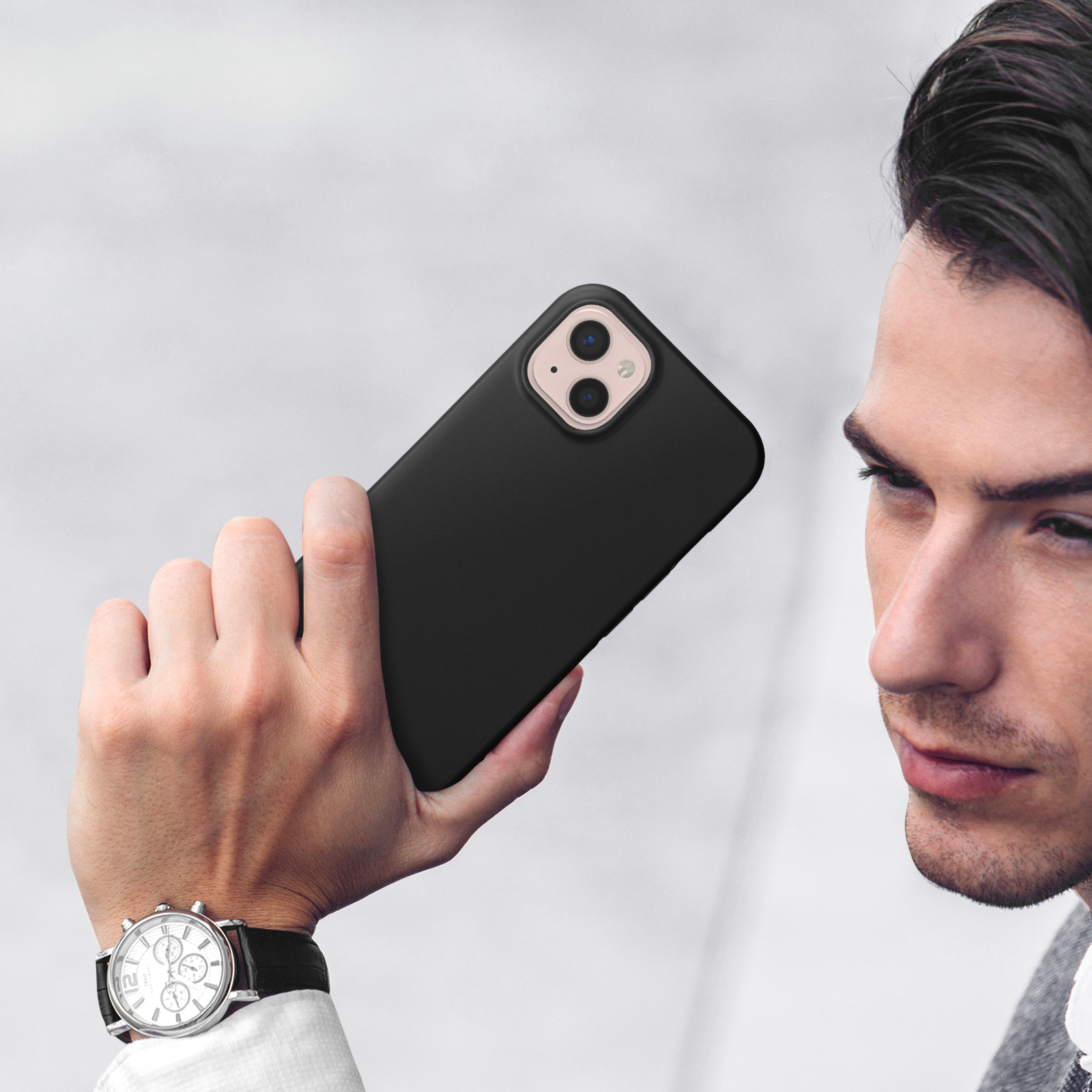 Uomo tiene uno smartphone nero con due fotocamere. Indossa un orologio.