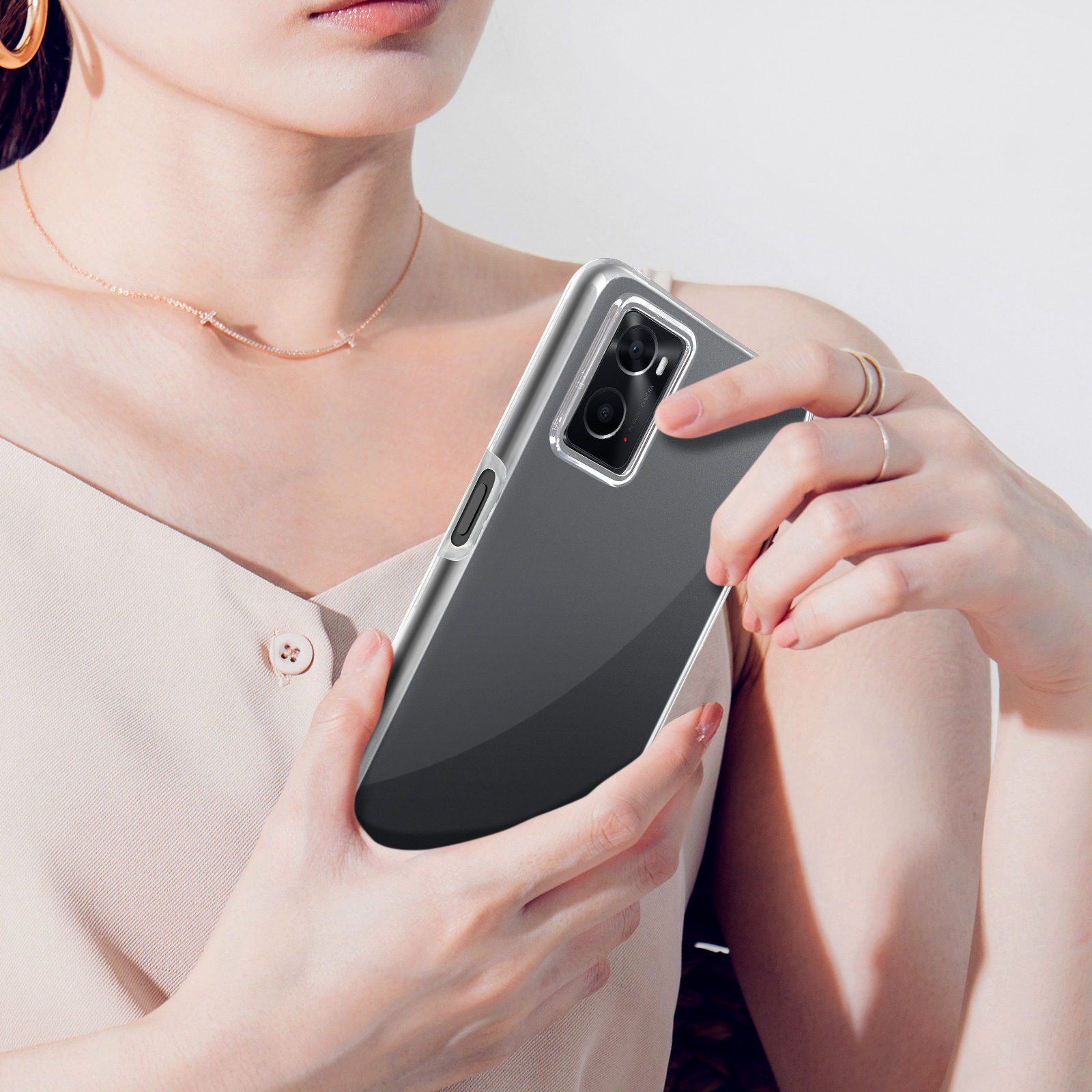 Une femme tient un smartphone avec une coque transparente devant elle.