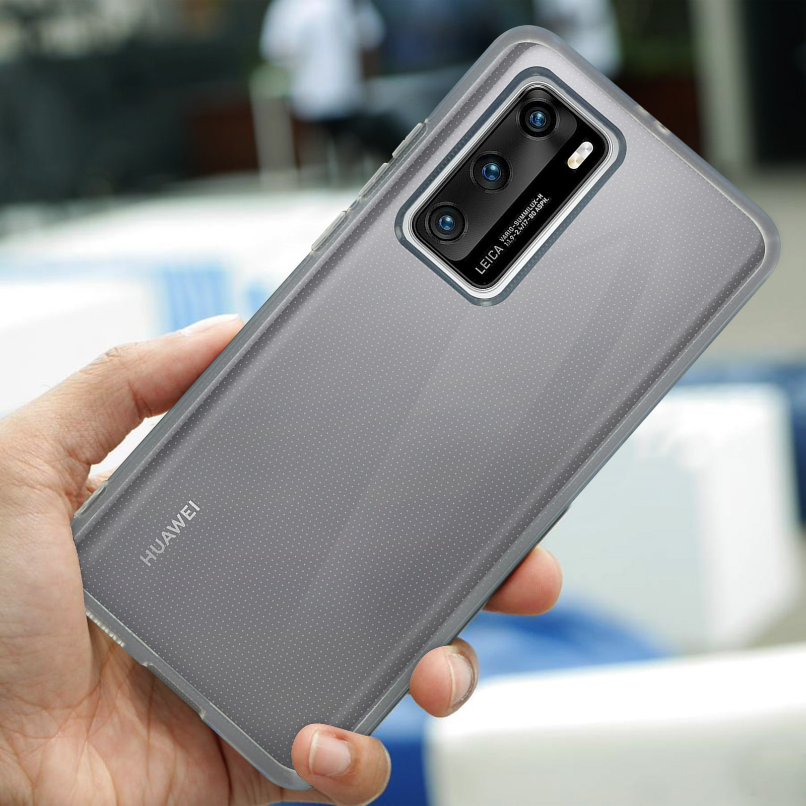 Une main tient un smartphone Huawei gris avec appareil photo Leica.