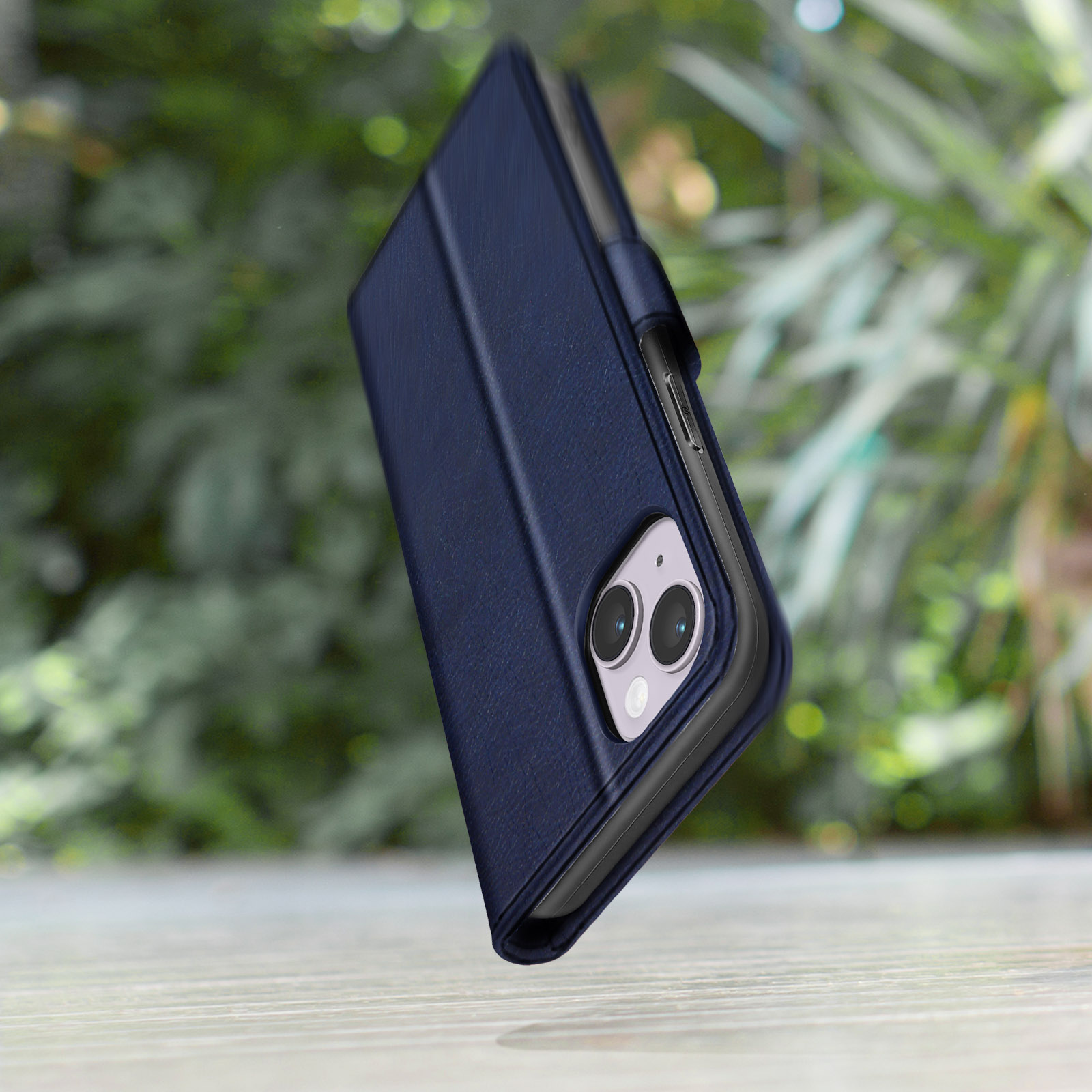 Donkerblauw telefoonhoesje met cameralenzen, tegen een wazige groene achtergrond.