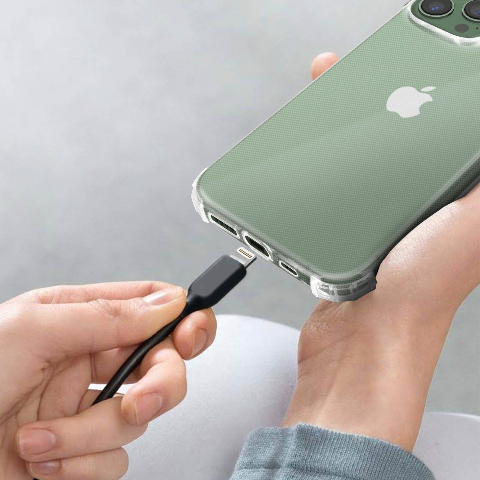 Een hand sluit een oplaadkabel aan op een groene iPhone in een hoesje.