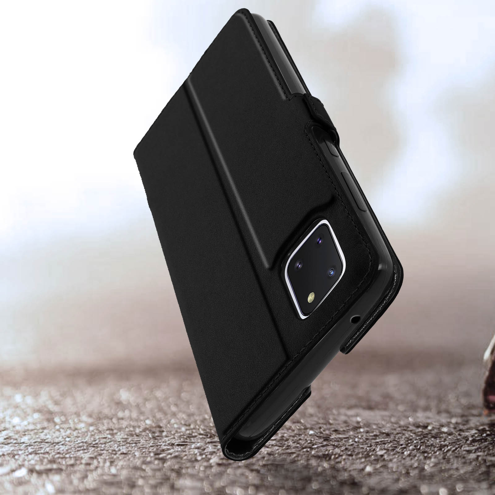 Téléphone noir avec étui à rabat, posé sur une surface texturée.