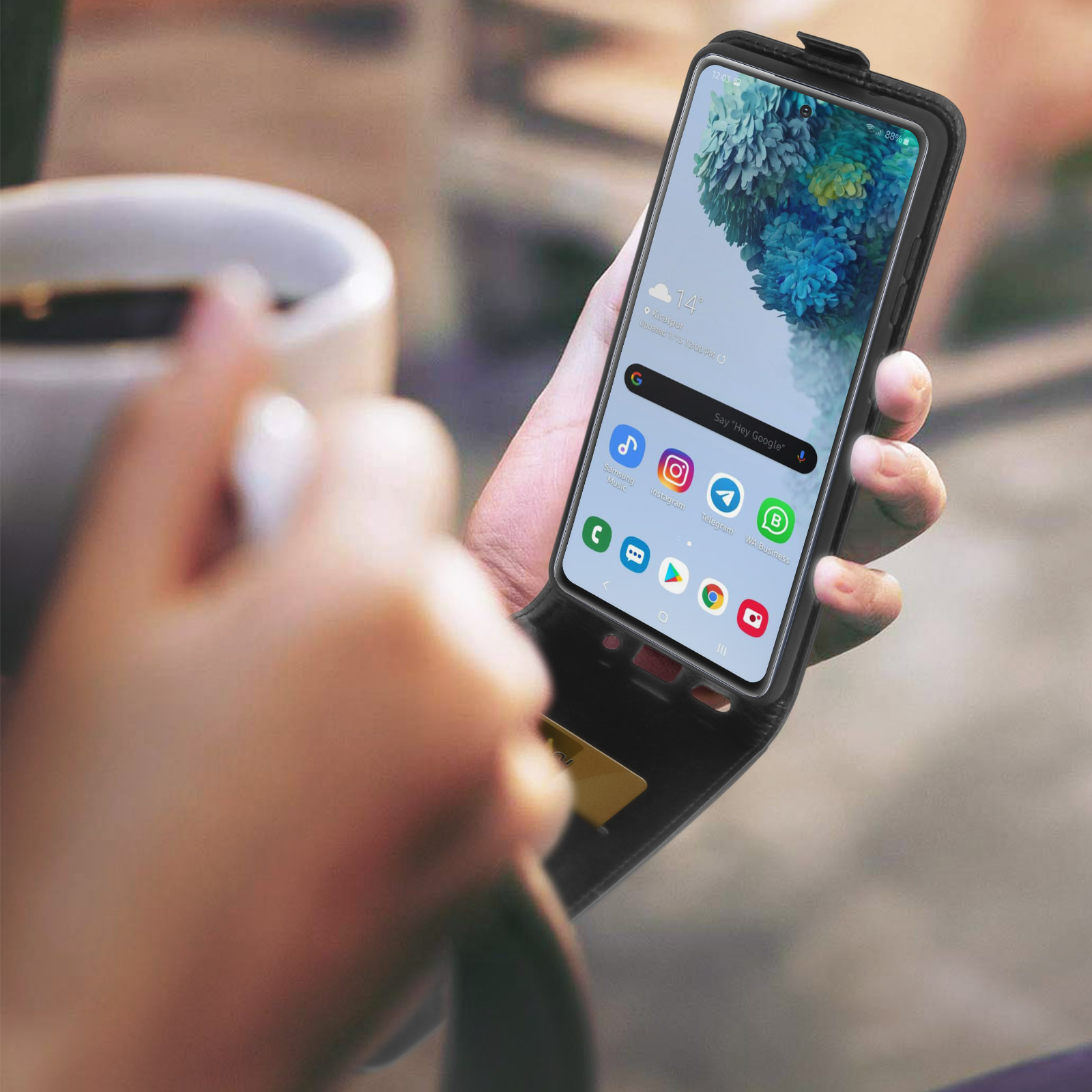 Una mano tiene uno smartphone con custodia aperta, visibile una carta dorata sul retro.