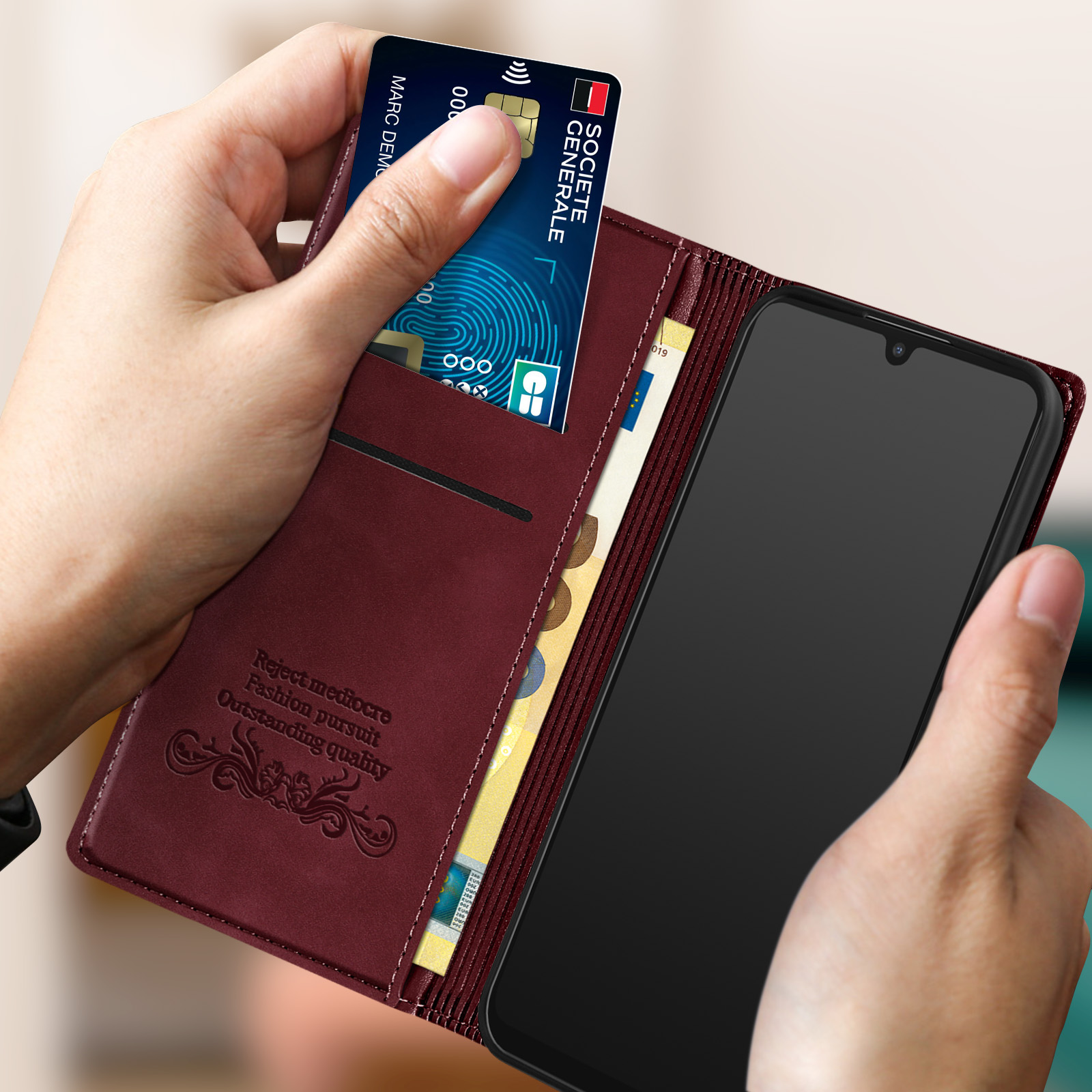 Een hand steekt een creditcard in een donkerrode portemonnee met een telefoon.