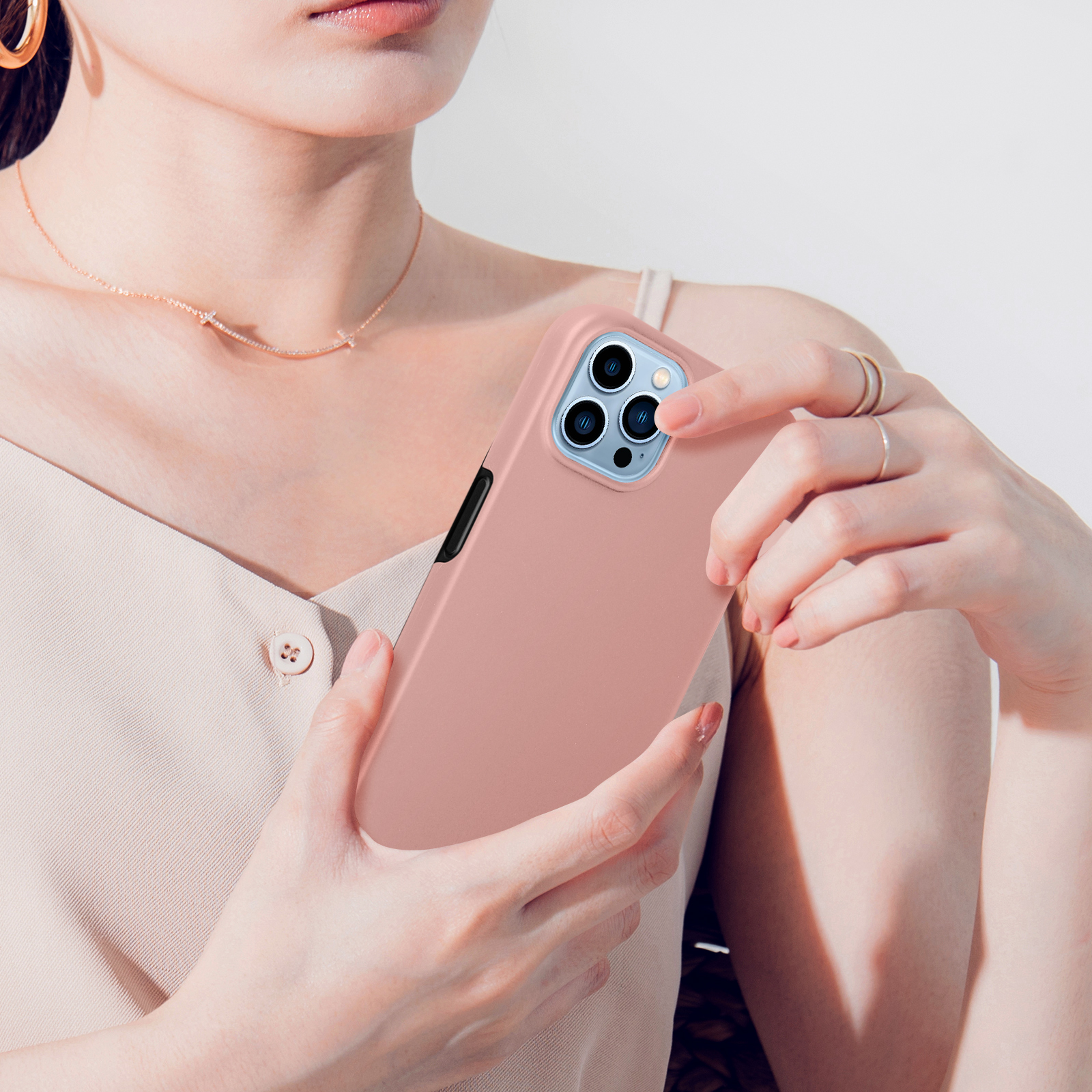 Une personne tient un téléphone rose à trois caméras.