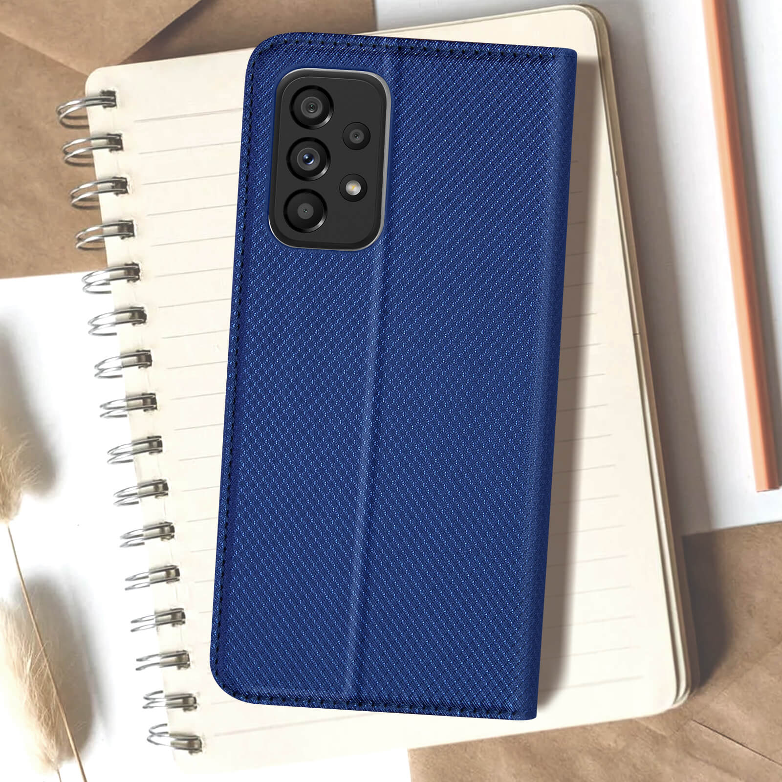 Étui de téléphone bleu sur carnet avec objectifs de caméra et crayon.