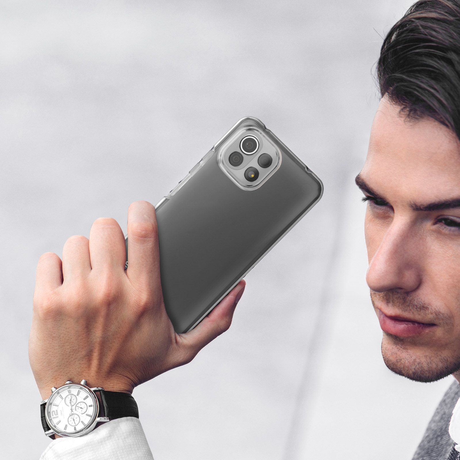 Un homme tient un téléphone transparent à quatre caméras sur fond clair.