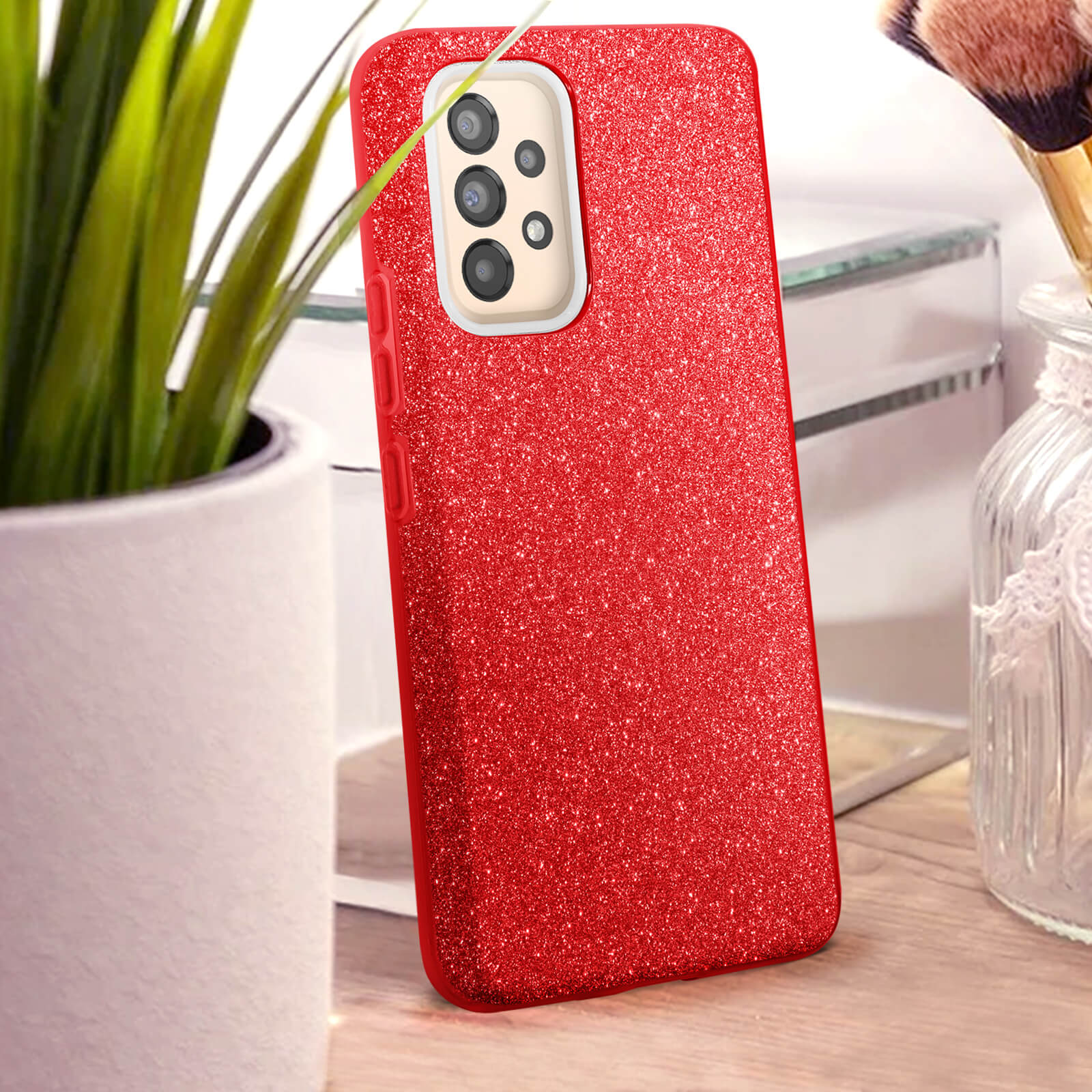 Coque de téléphone rouge pailletée avec découpe appareil photo, à côté d'une plante.