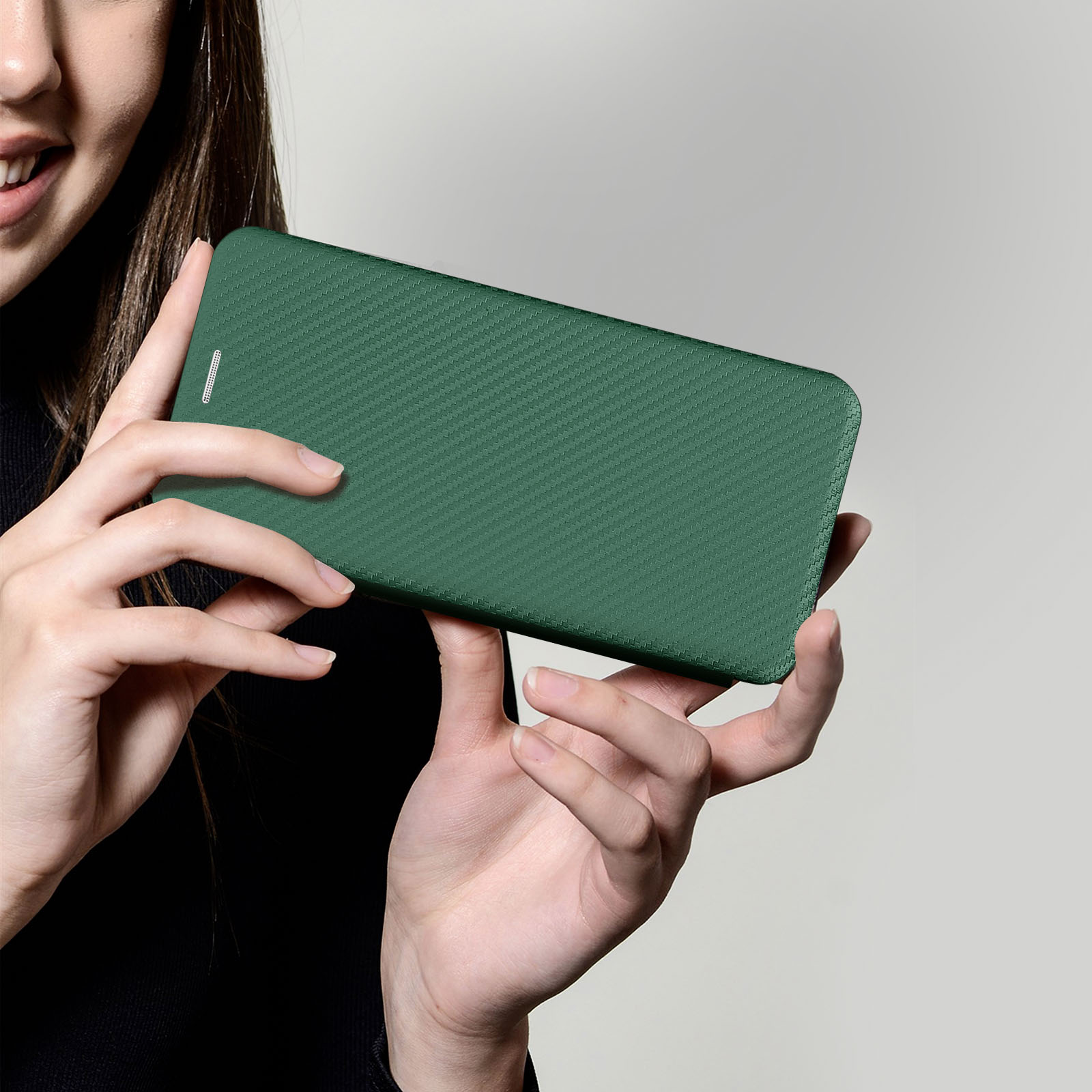 Vrouw in het zwart houdt een groene telefoonhoes met textuur vast. Close-up.