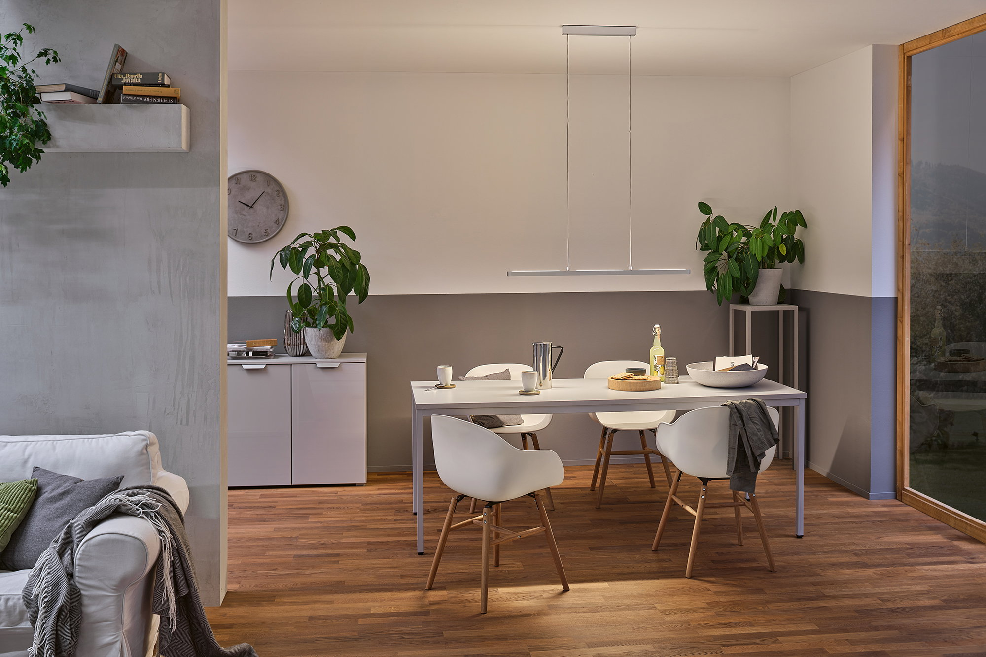 Sala da pranzo moderna con tavolo, sedie, illuminazione e finestra bianchi.