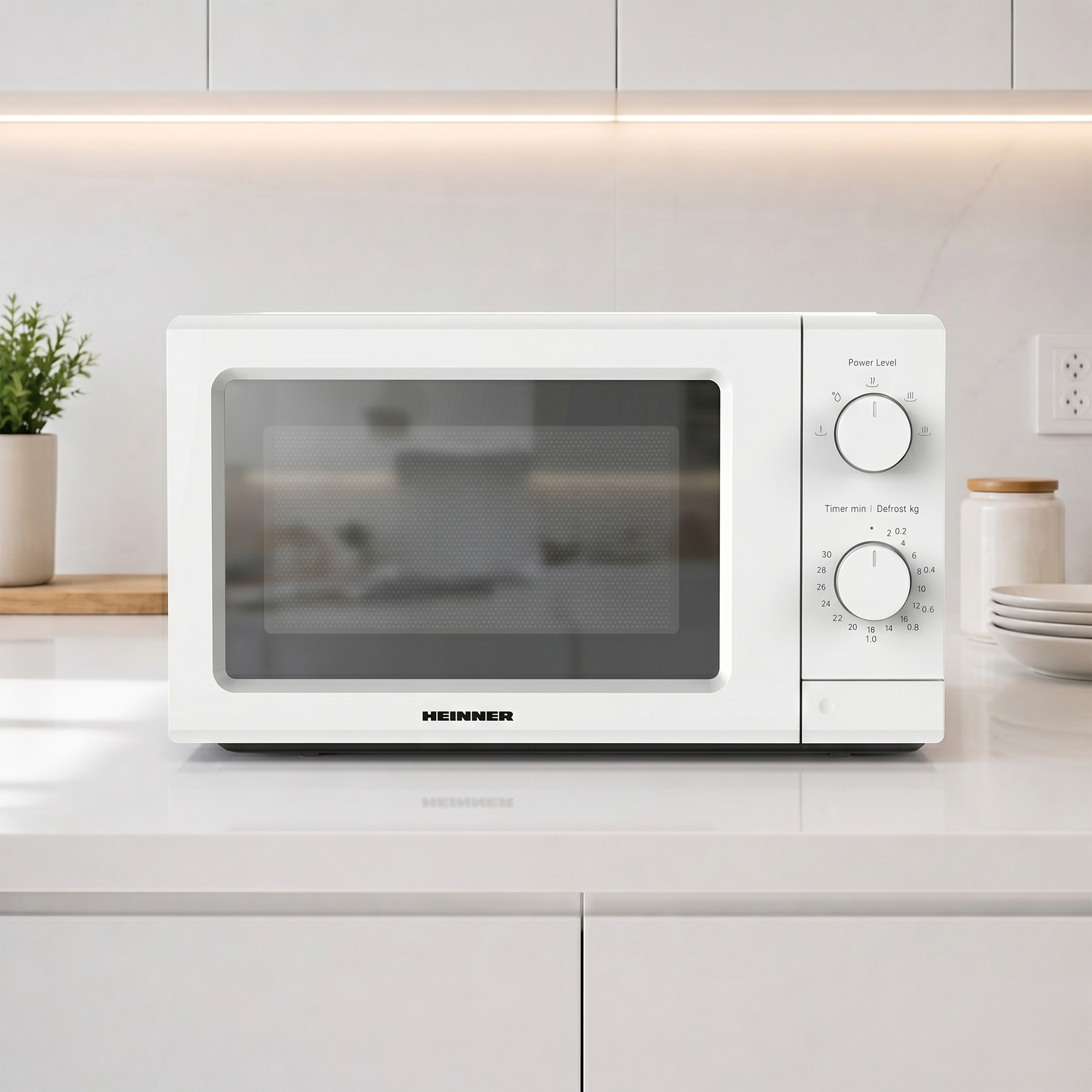A white HEINNER microwave sits on a countertop with control knobs.