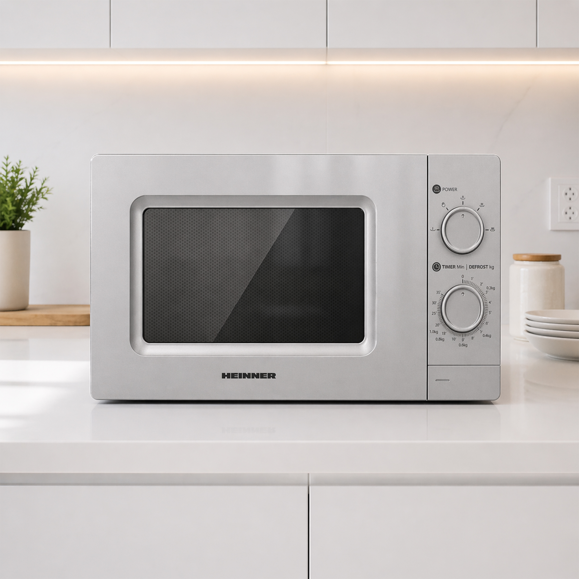 A silver HEINNER microwave oven is placed on a white countertop.