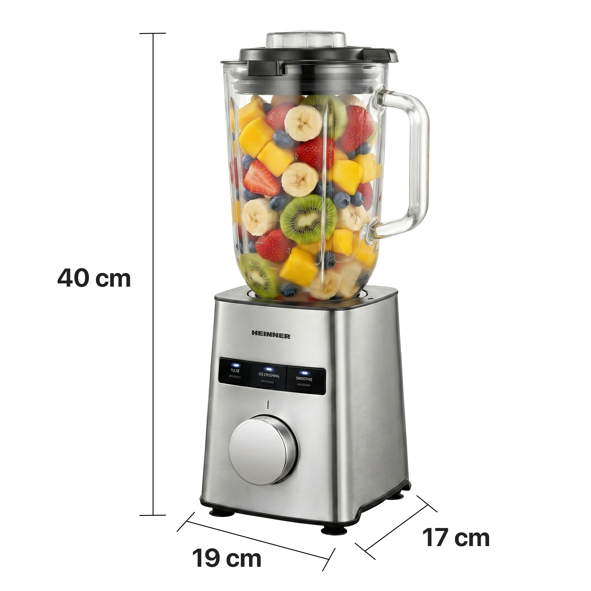 Stainless steel blender with glass jar full of colorful fruit. Dimensions 40x19x17 cm.