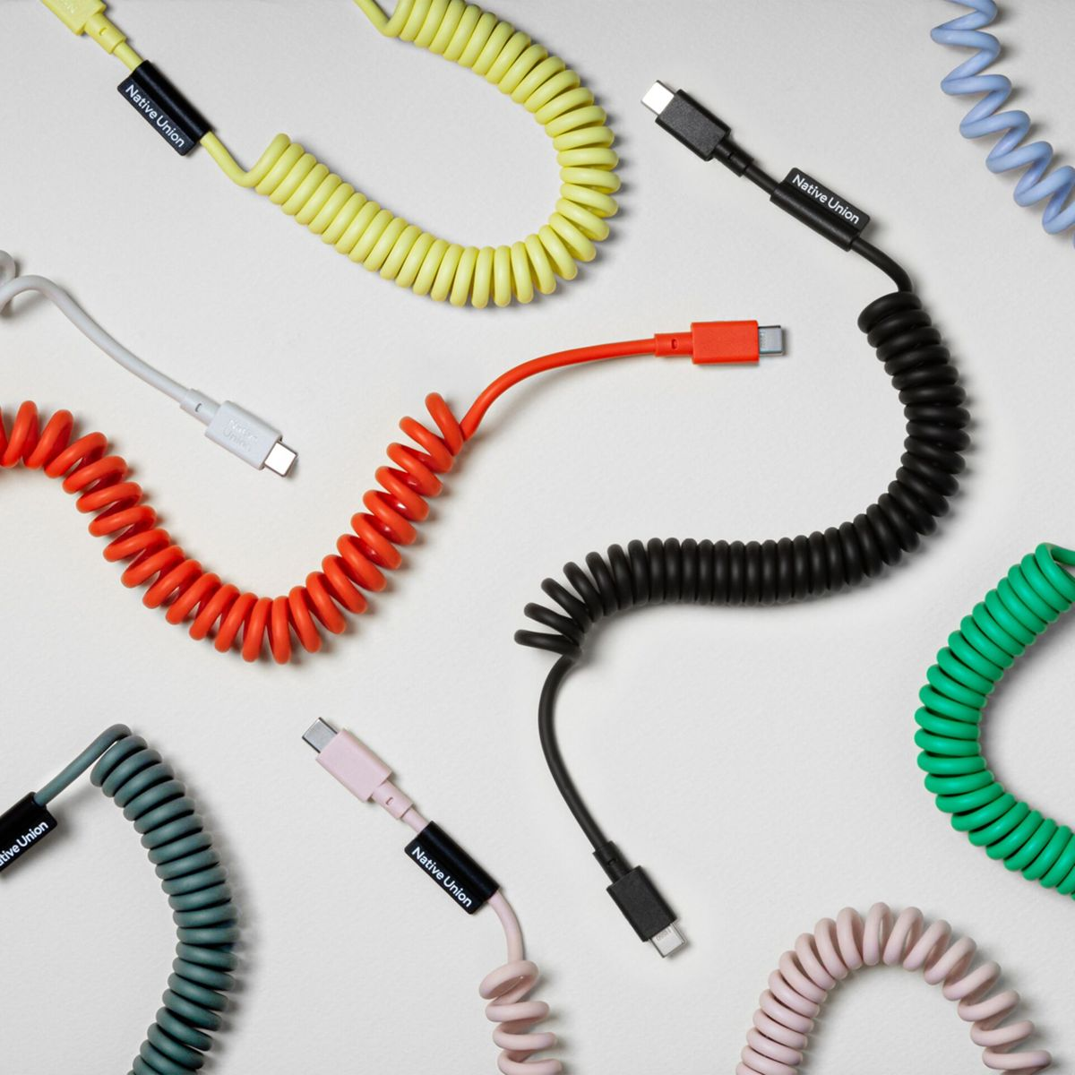 Plusieurs câbles spiralés colorés avec connecteurs USB-C sur fond blanc.