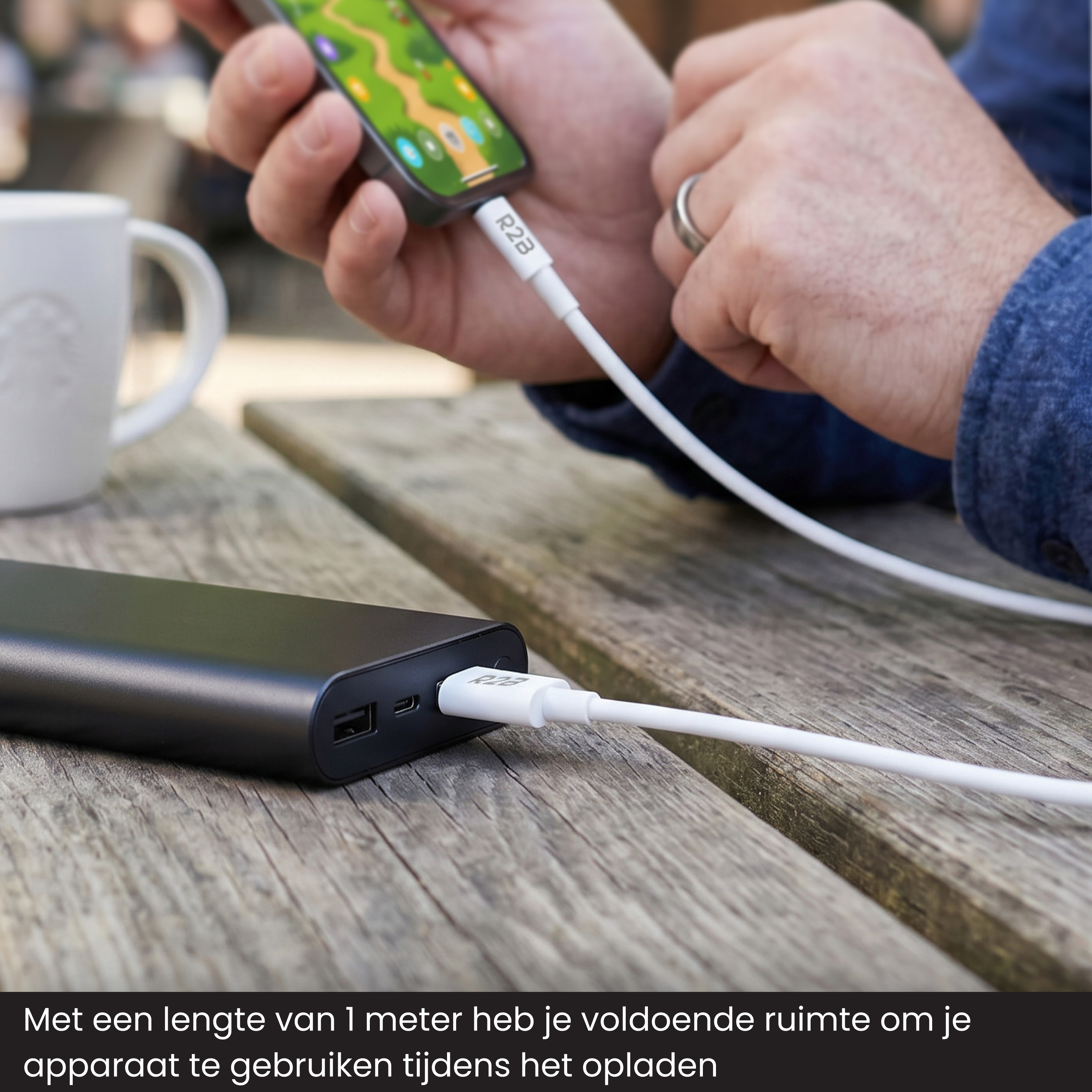 A black power bank charges a smartphone via a white cable.