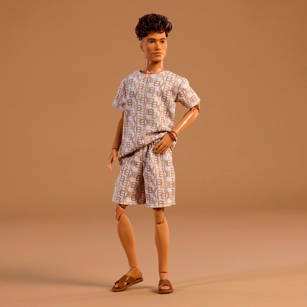 Ein Mann-Puppe in einem gemusterten Outfit und Sandalen steht vor einem braunen Hintergrund.