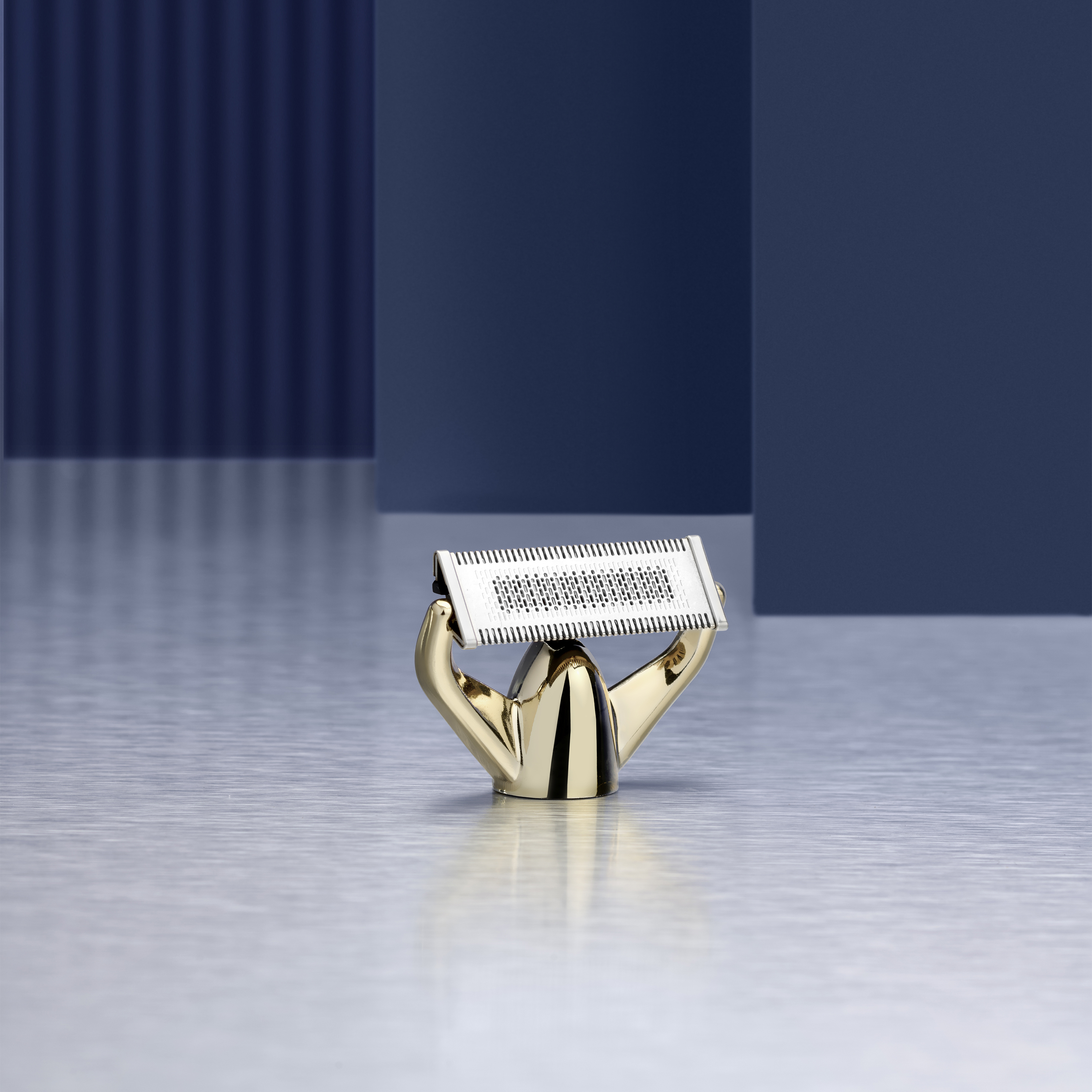 Een gouden scheerkopopzetstuk met zilveren foliekop op geborsteld metaal.